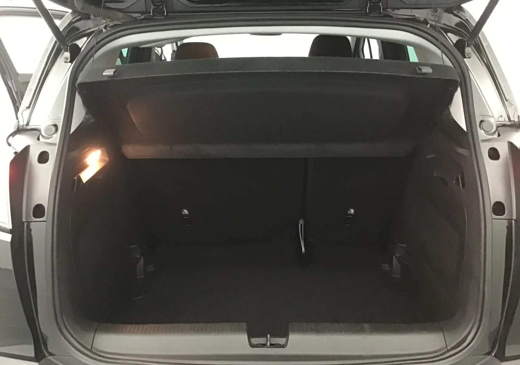 Coffre ouvert vu de l'arrière d'un Opel Crossland noir 2022, montrant un espace de chargement vide et éclairé.