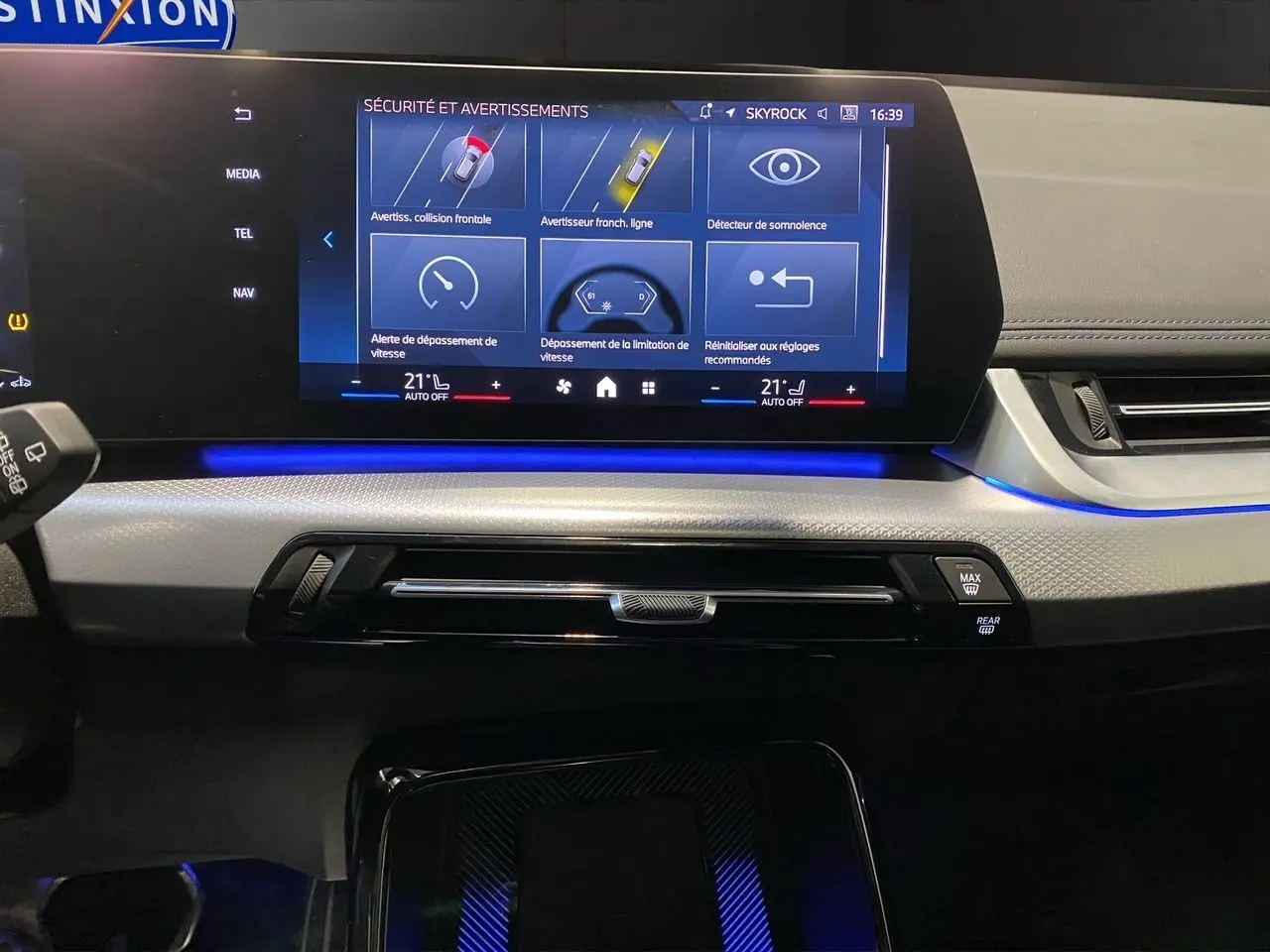 Tableau de bord intérieur de BMW X1 2025 avec écran tactile affichant les alertes de sécurité, ambiance lumineuse bleue.