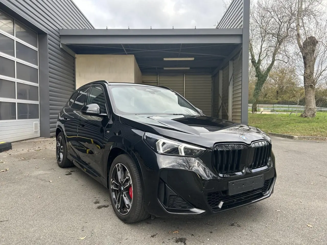BMW X1 XDRIVE 20D M SPORT 2025 noir Black Saphire en 3/4 avant avec jantes sport et étriers rouges visibles