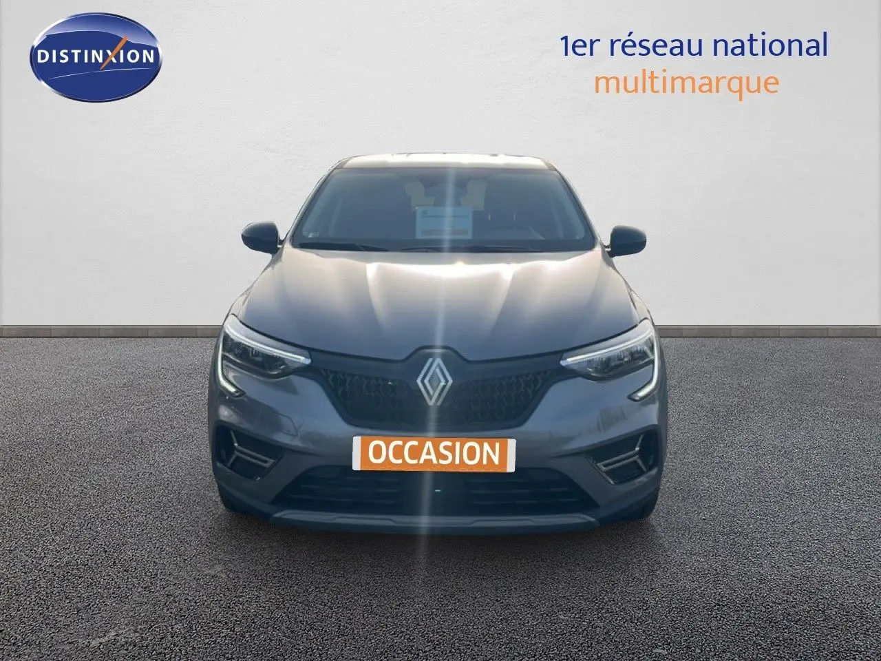Vue frontale d'un Renault Arkana gris satin métal 2025 avec calandre noire et logo Renault bien visible.
