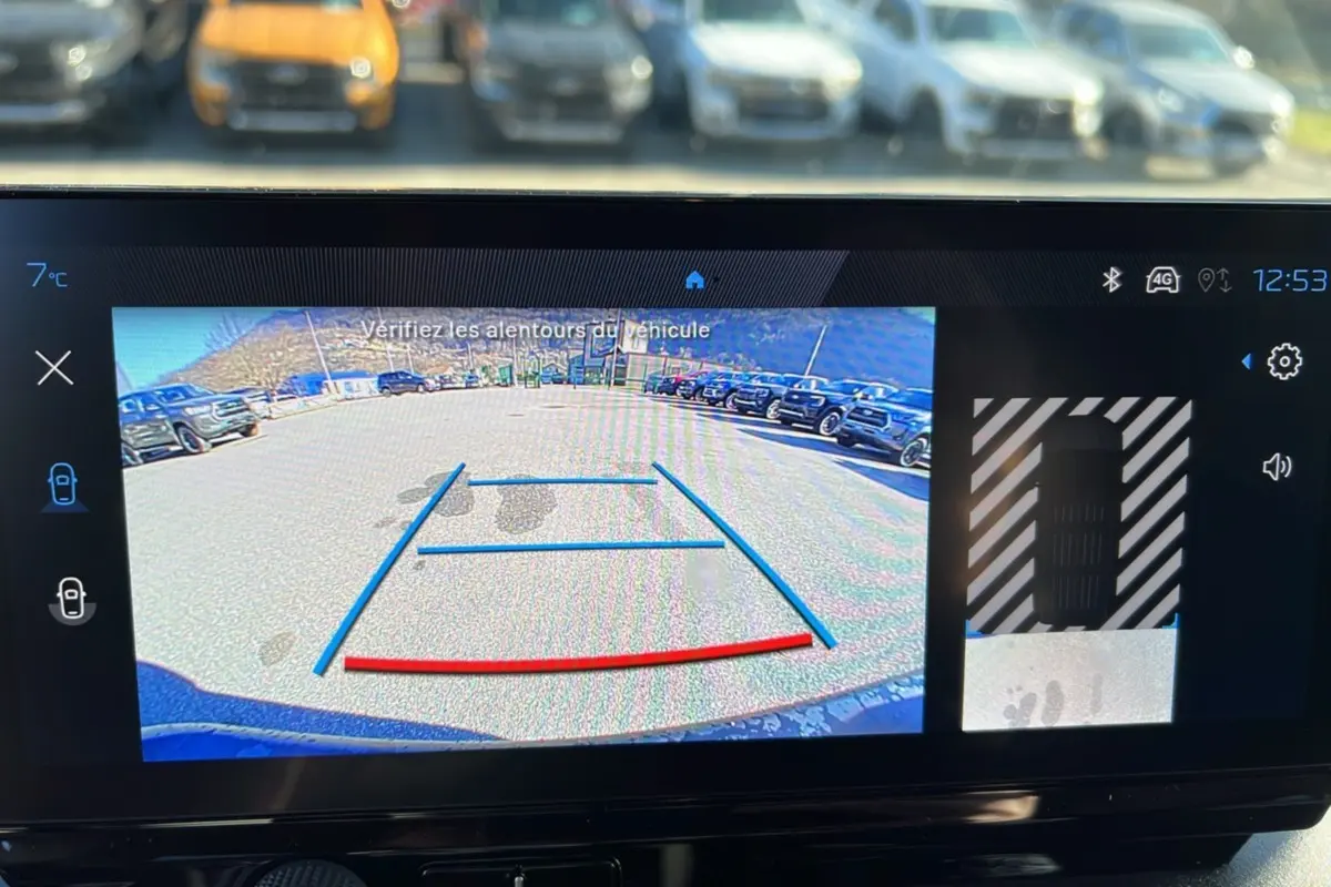 Écran de caméra de recul du Peugeot Rifter vert Sirkka, vue arrière avec lignes de guidage et parking visible.