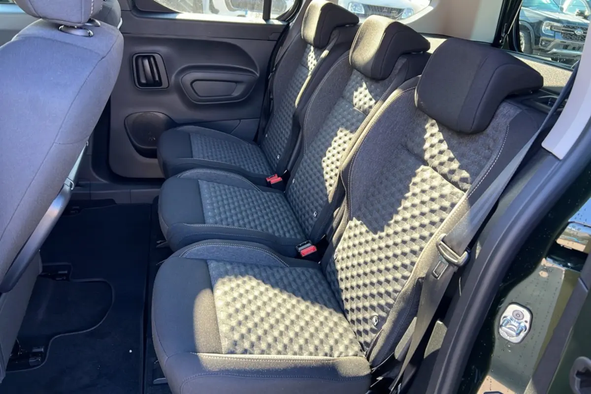 Vue intérieure côté droit des sièges arrière en tissu gris du Peugeot Rifter Vert Sirkka 2025, avec porte ouverte.