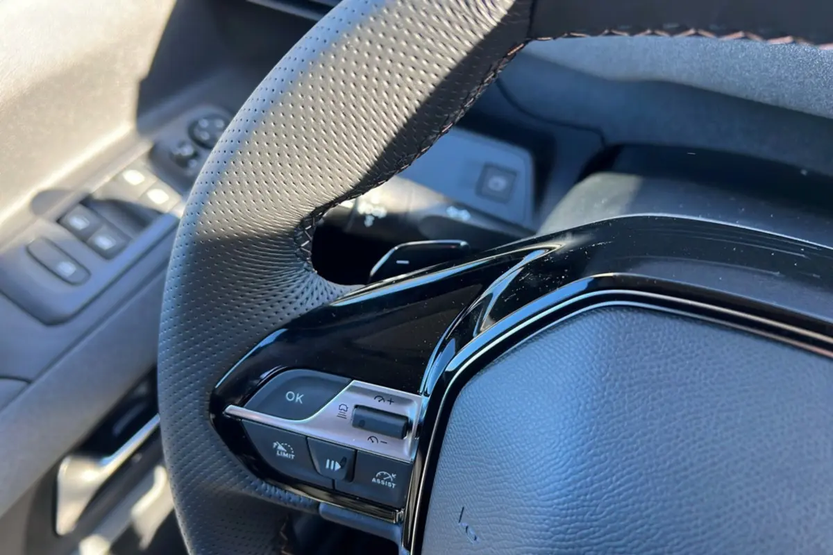 Gros plan sur le volant cuir multifonctions côté gauche du Peugeot Rifter 2025, avec commandes intégrées et finition noire brillante.