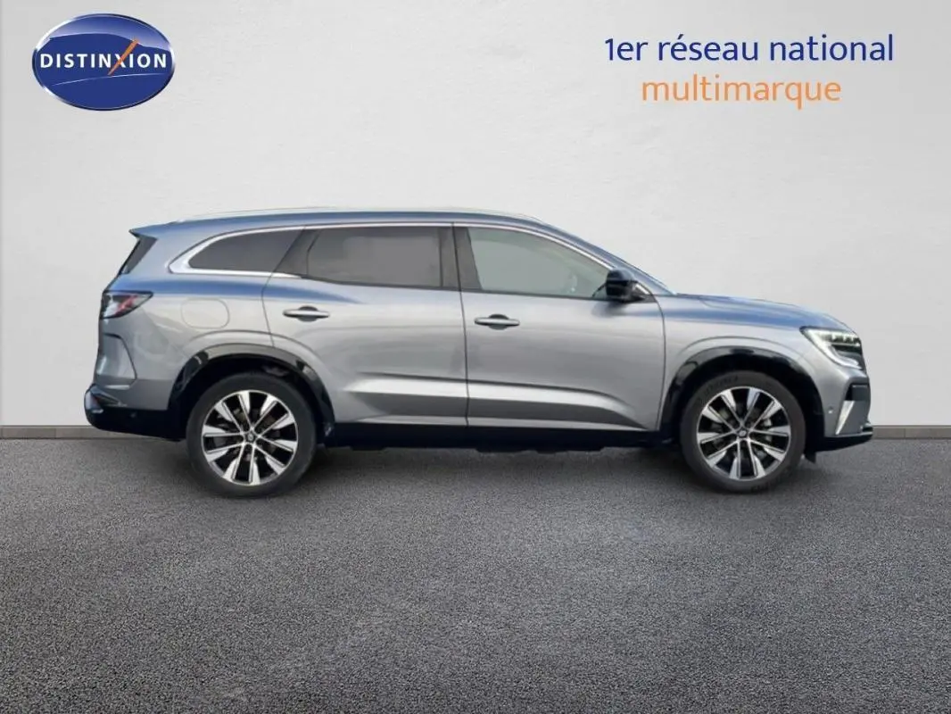 Profil côté droit du Renault Espace gris 2024 avec barres de toit et jantes aluminium visibles.