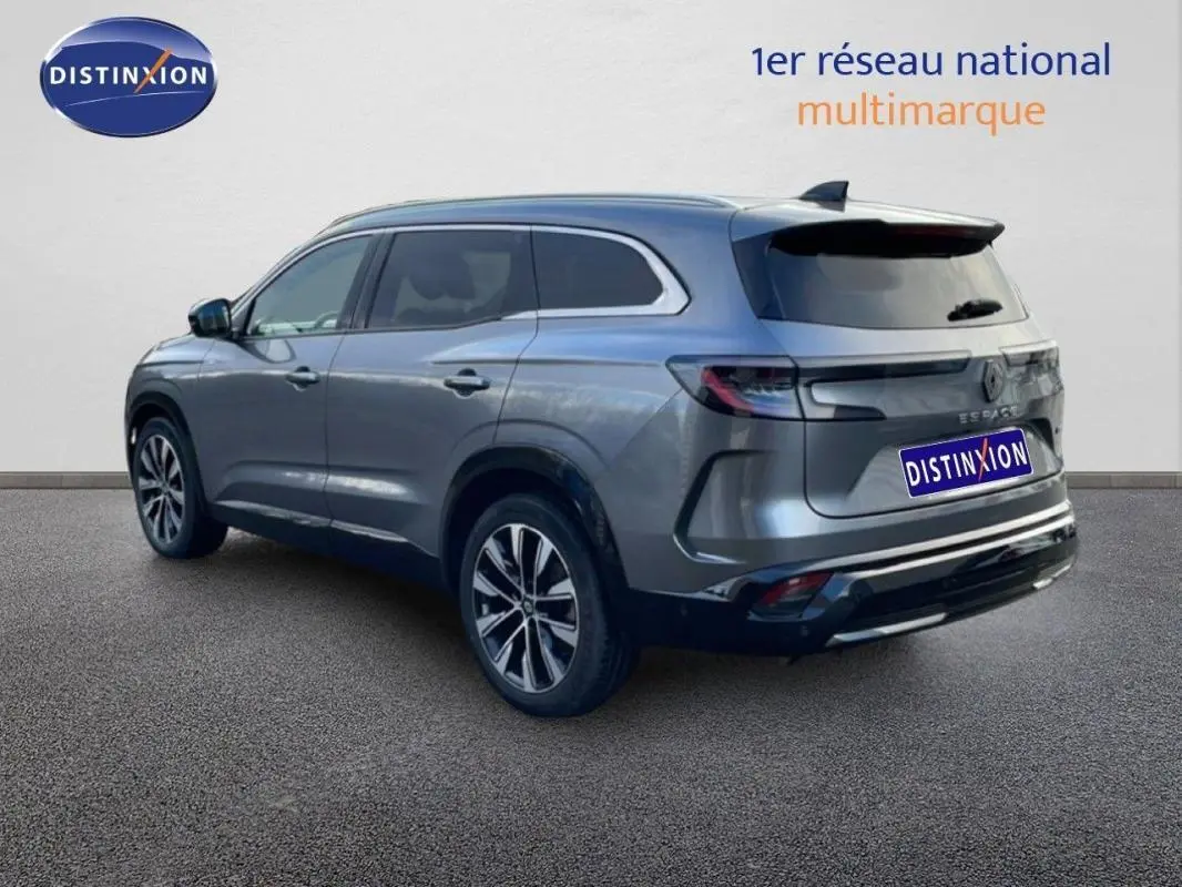 Vue 3/4 arrière droite d'un Renault Espace gris 2024 avec barres de toit et jantes aluminium.