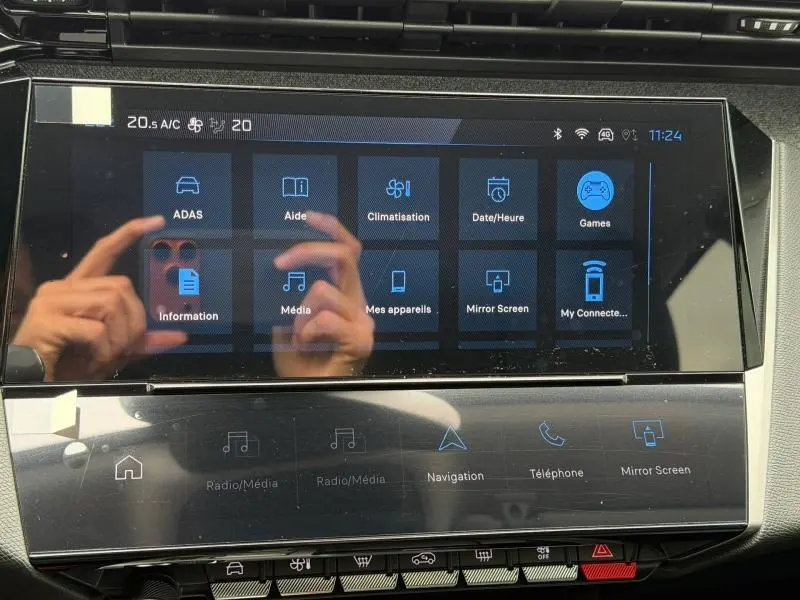 Écran tactile central de la Peugeot 308 blanc Okénite, affichant le menu des fonctions connectées en intérieur.