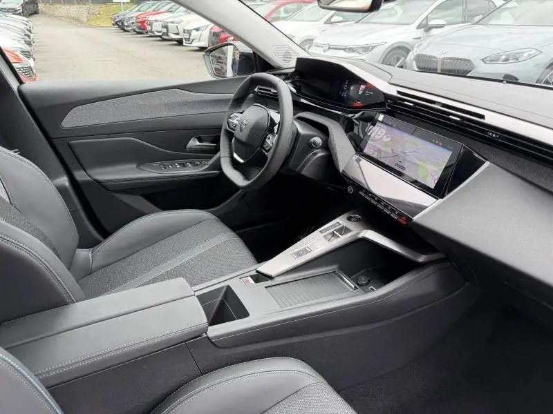 Vue intérieure côté conducteur de la Peugeot 308 1.2 Hybrid 145ch Allure 2025, avec tableau de bord numérique et écran tactile.