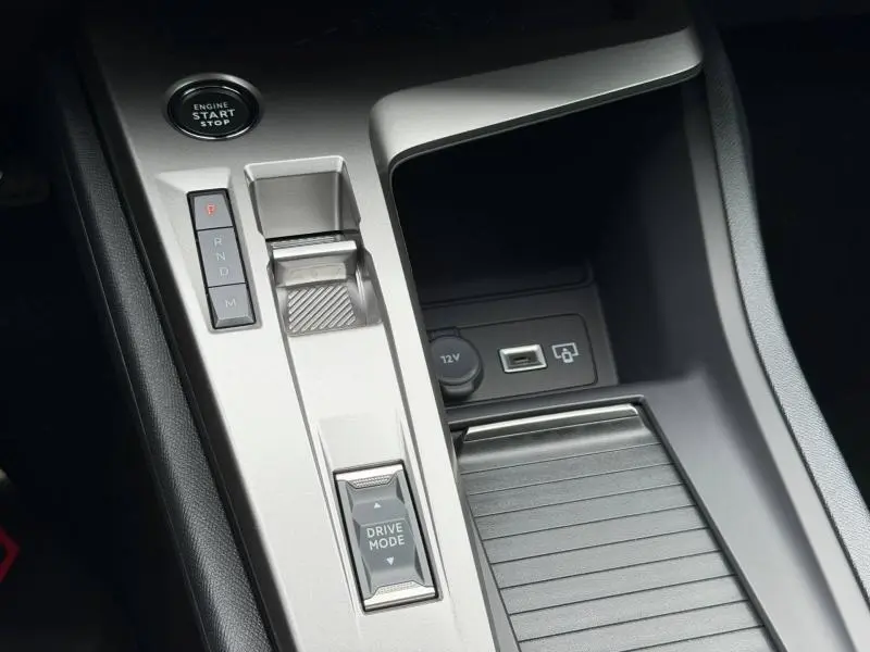Gros plan sur la console centrale de la Peugeot 308 Hybrid blanche, montrant la commande de boîte auto et prises USB/12V.