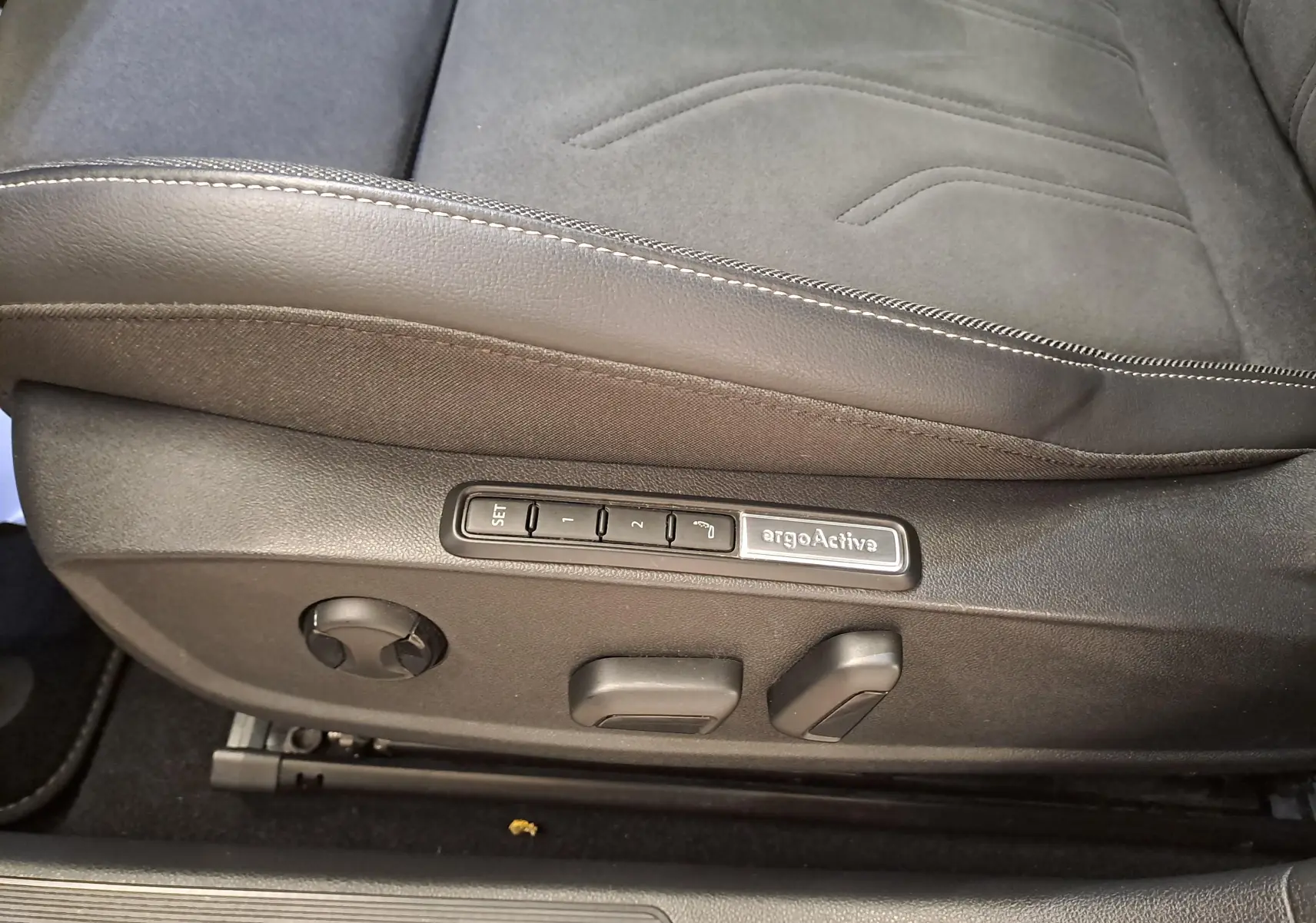 Détail du côté gauche du siège conducteur en cuir et tissu avec commandes de réglage mémoire ErgoActive sur Volkswagen Golf Bleu Anémone.