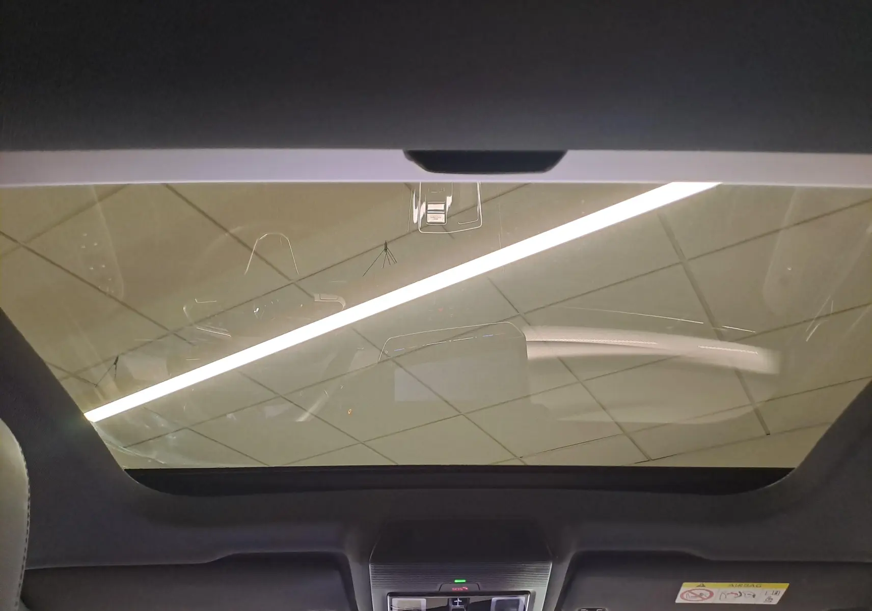 Vue intérieure du toit ouvrant panoramique de la Volkswagen Golf 1.5 eTSI Bleu Anémone avec commandes intégrées au plafond.