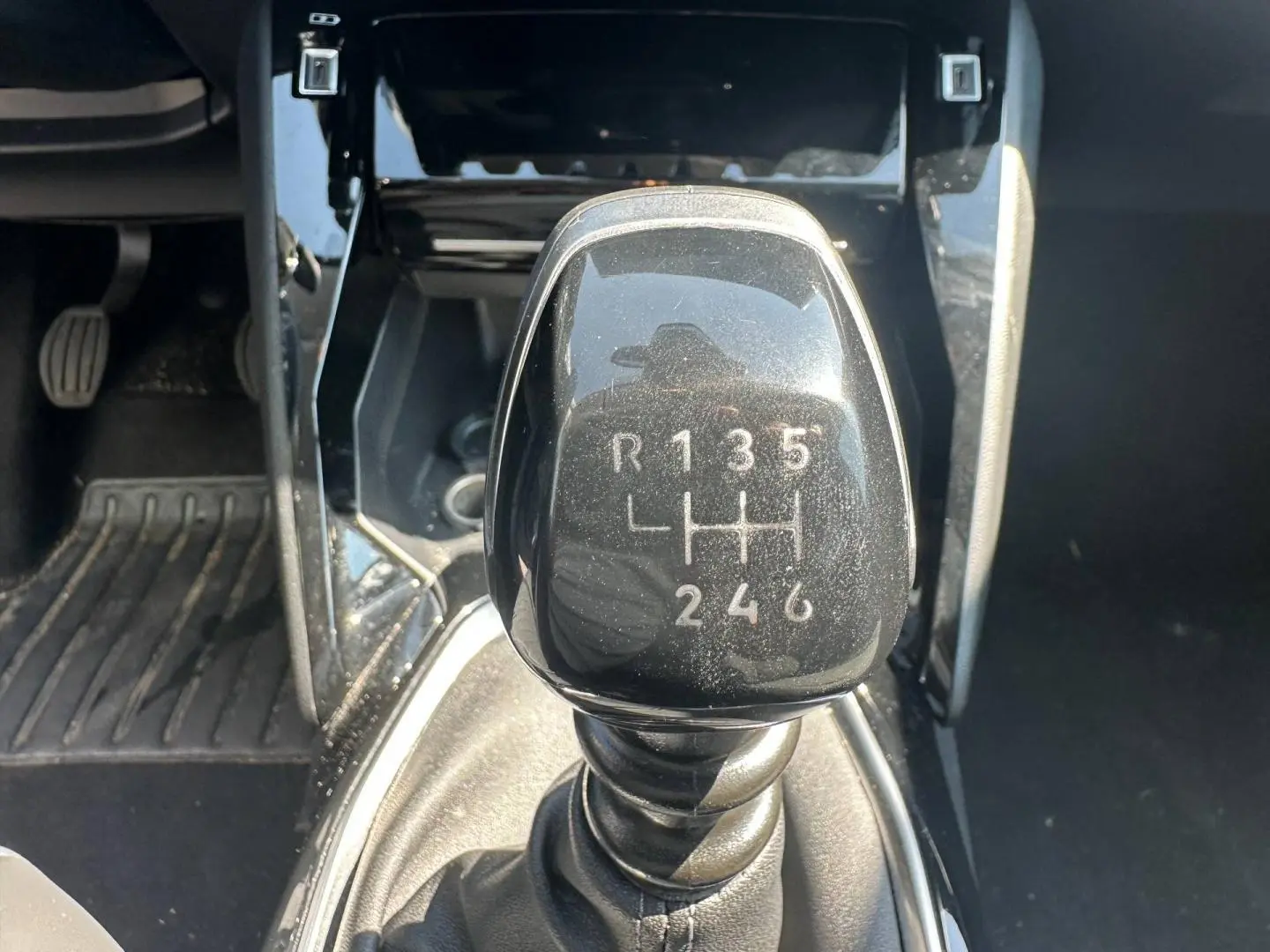 Gros plan sur le levier de vitesses manuel noir de la Peugeot 208 1.2 100ch, entouré de la console centrale noire.