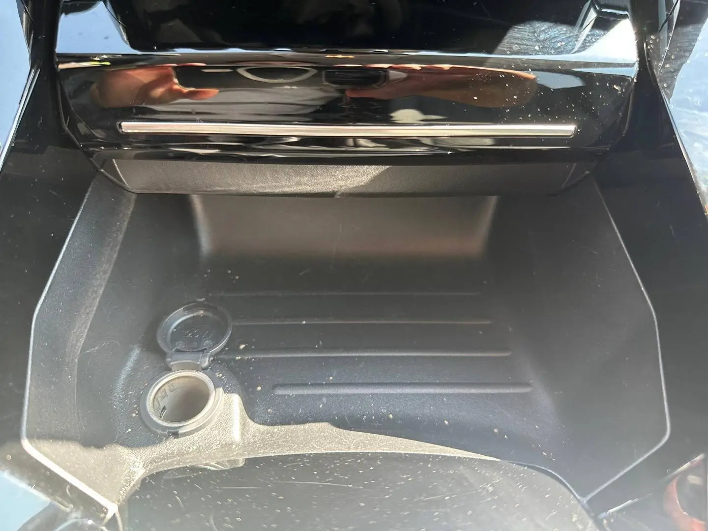 Compartiment de rangement intérieur ouvert avec prise 12V visible sur Peugeot 208 gris Selenium 2025.
