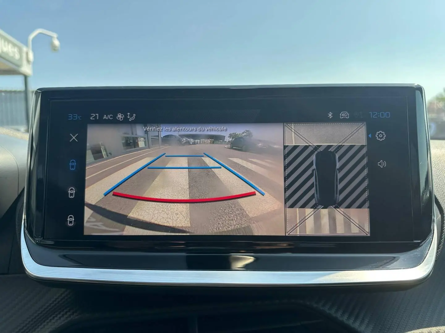 Écran tactile intérieur montrant la caméra de recul et l’aide au stationnement de la Peugeot 208 gris Selenium.