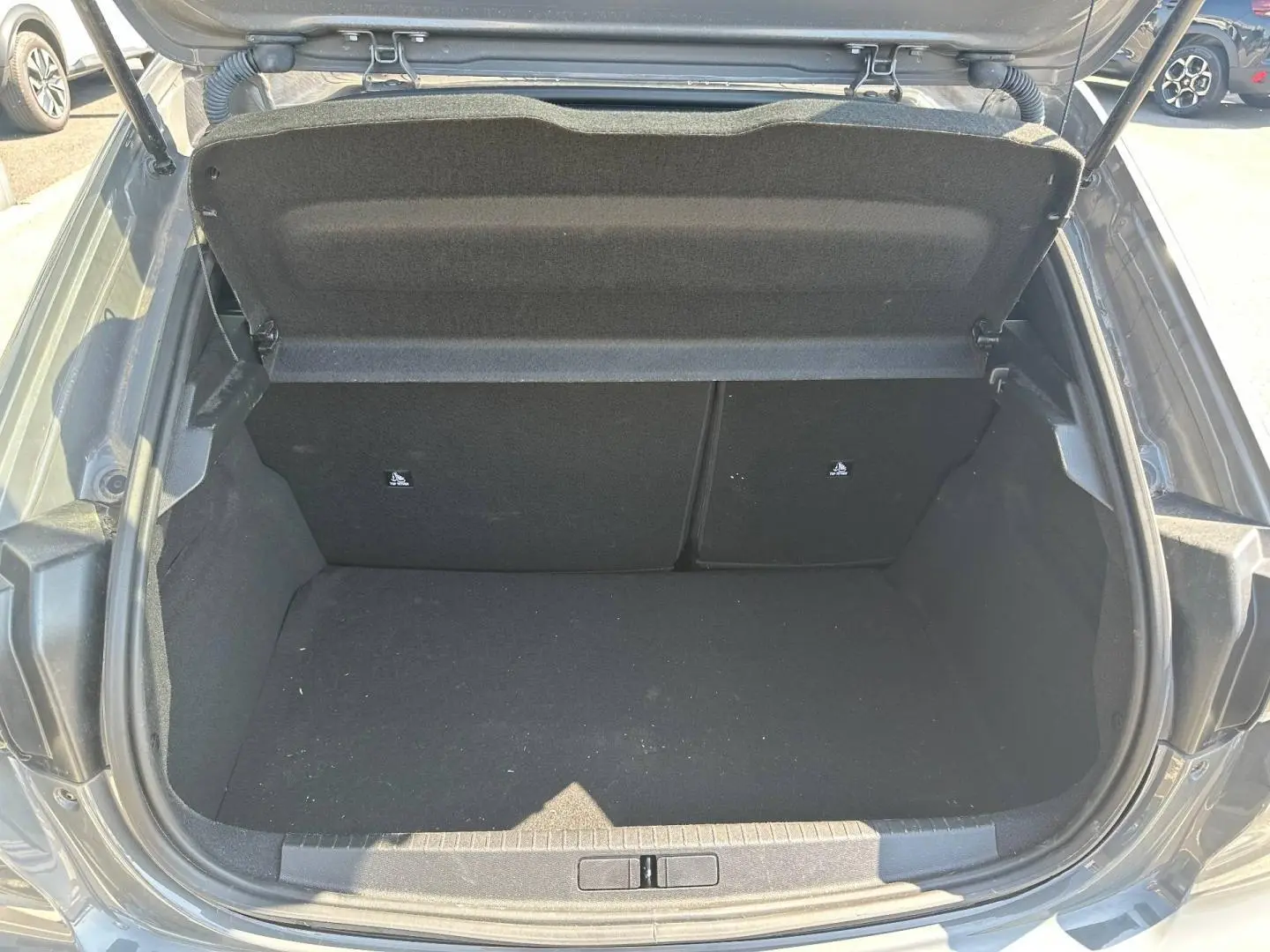Coffre ouvert vu de l'arrière d'une Peugeot 208 1.2 100ch gris Selenium avec banquette arrière rabattable.