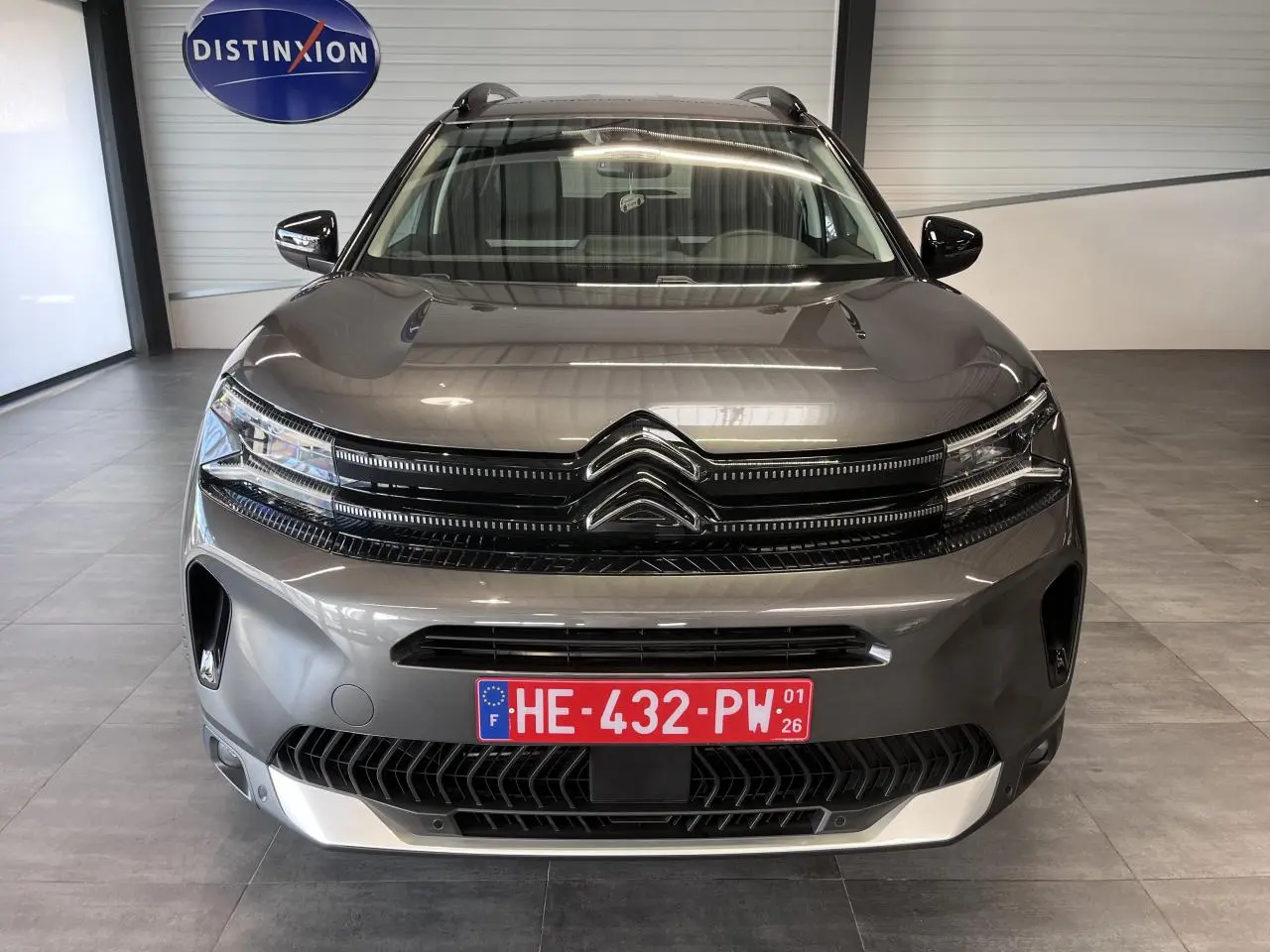 Vue frontale d'un Citroën C5 Aircross gris platinium avec calandre noire brillante et plaque d'immatriculation rouge.