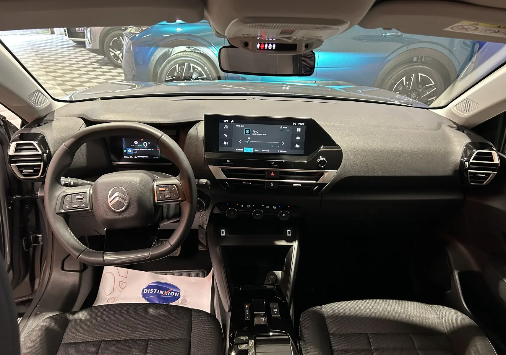 Vue intérieure avant du Citroën E-C4 gris foncé 2025, avec tableau de bord numérique et écran tactile central lumineux.