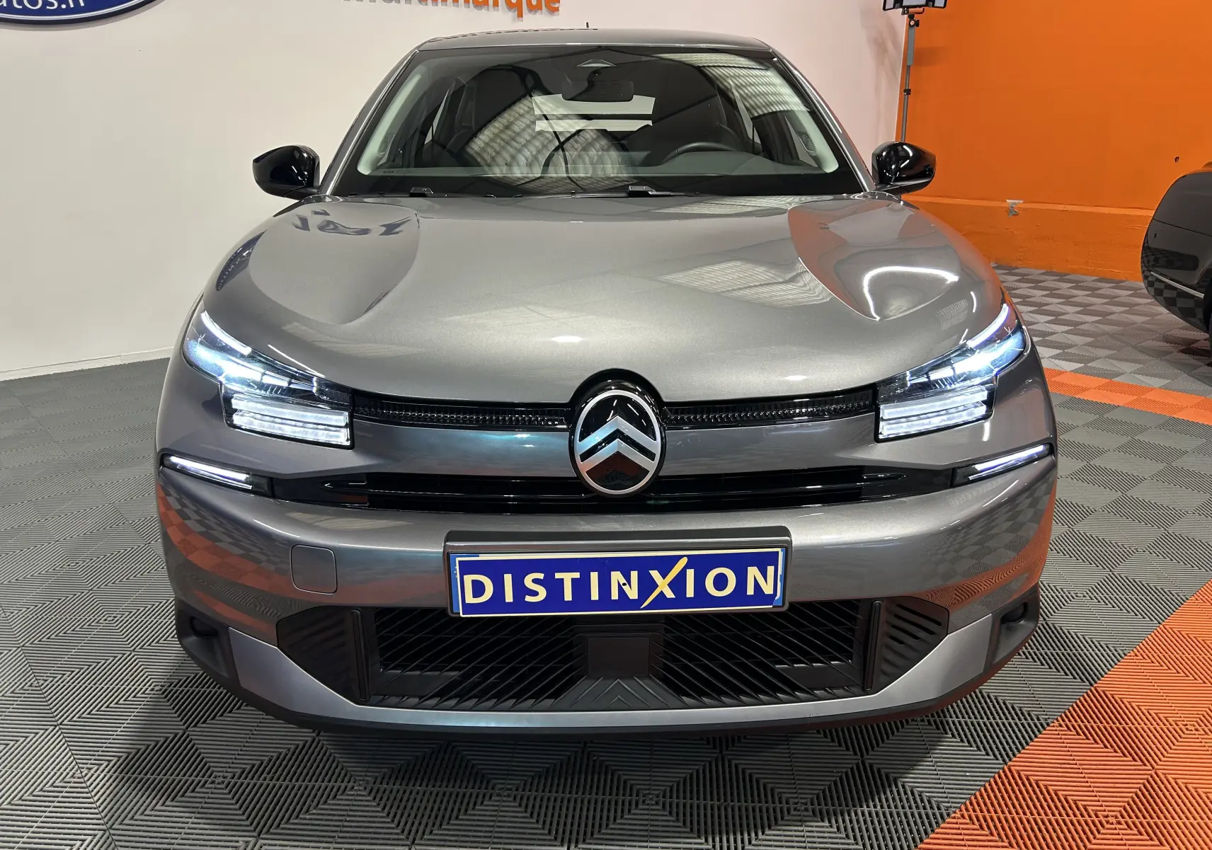 Vue de face du Citroën E-C4 gris foncé avec phares LED allumés et calandre marquée du logo double chevron.