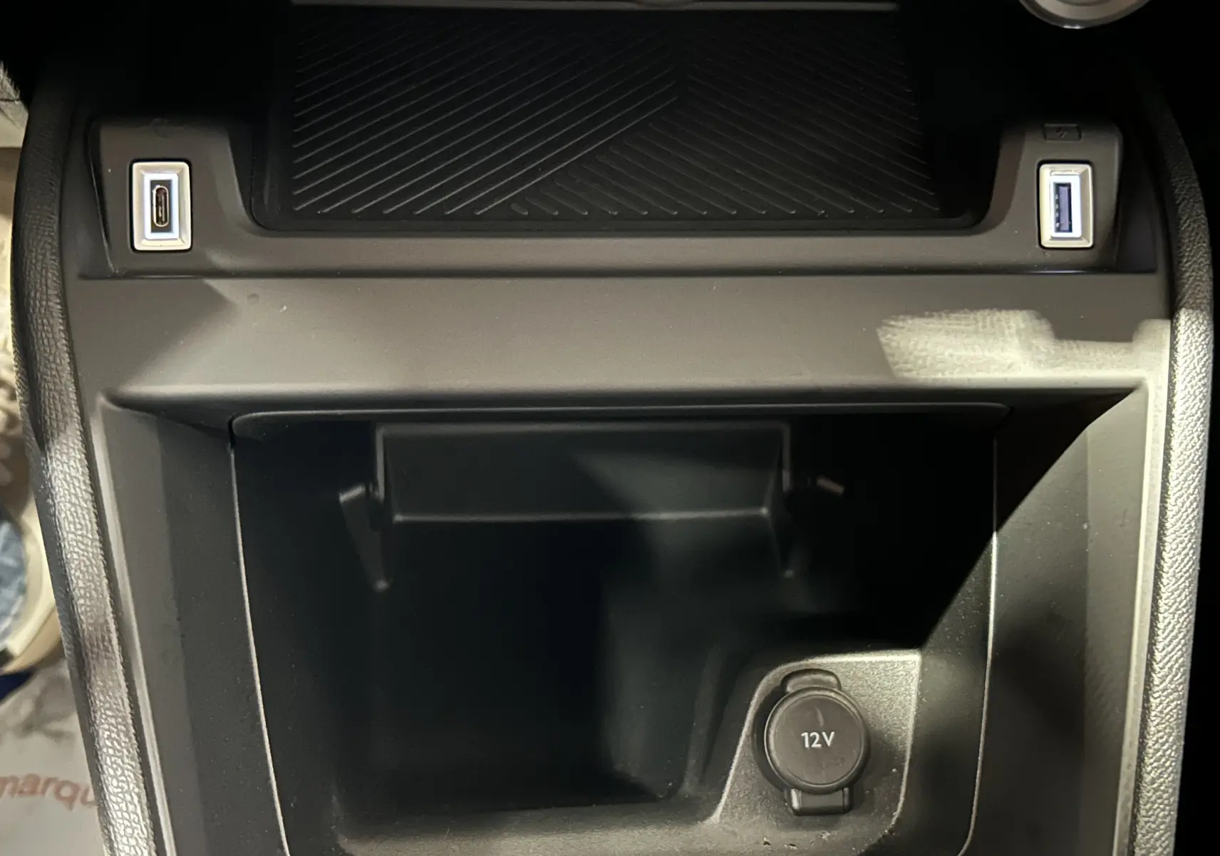 Gros plan sur la console centrale noire du Citroën E-C4 2025, avec prises USB et prise 12V visibles.