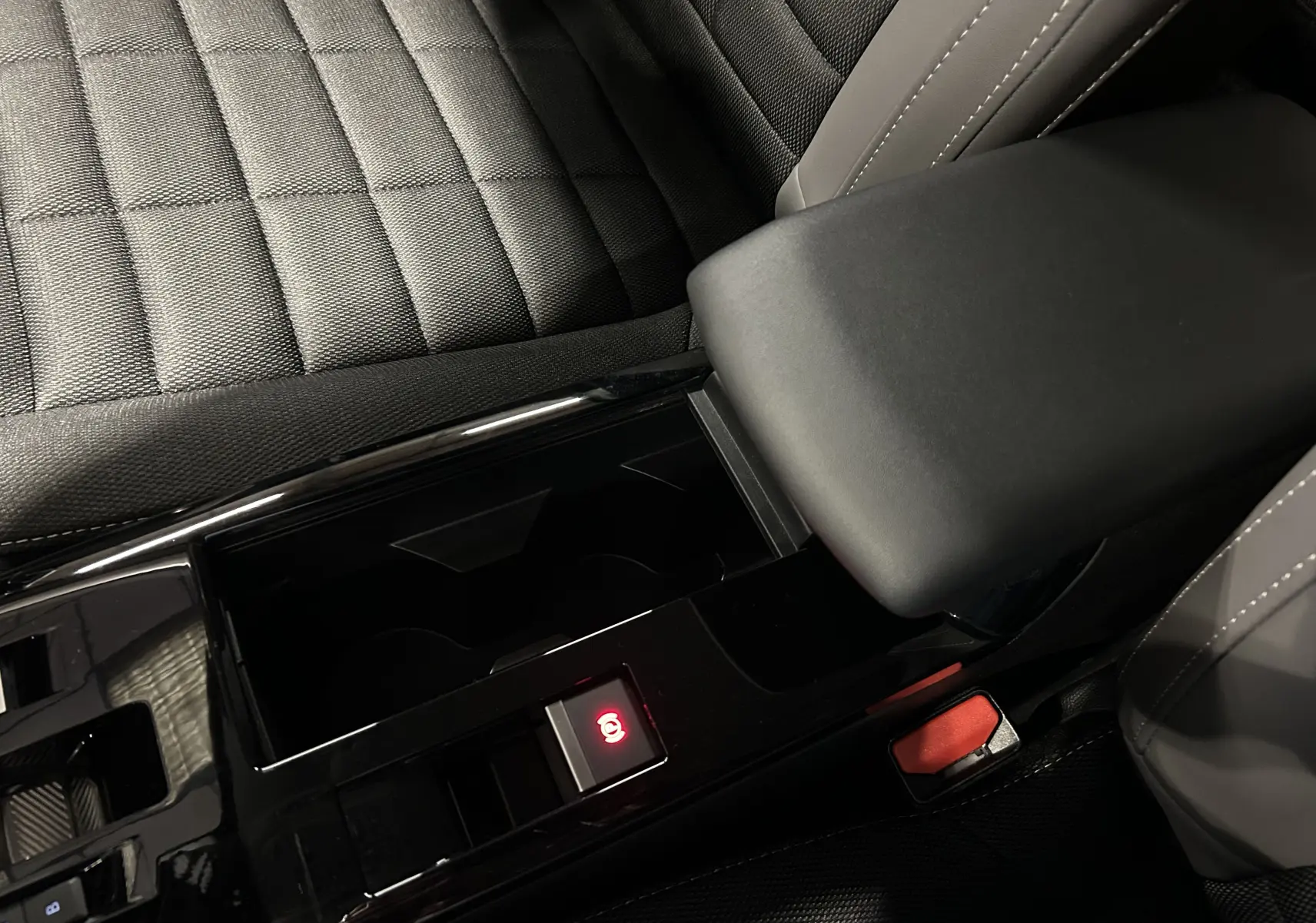 Gros plan sur la console centrale noire et accoudoir gris foncé du Citroën E-C4 électrique 2025, intérieur tissu.