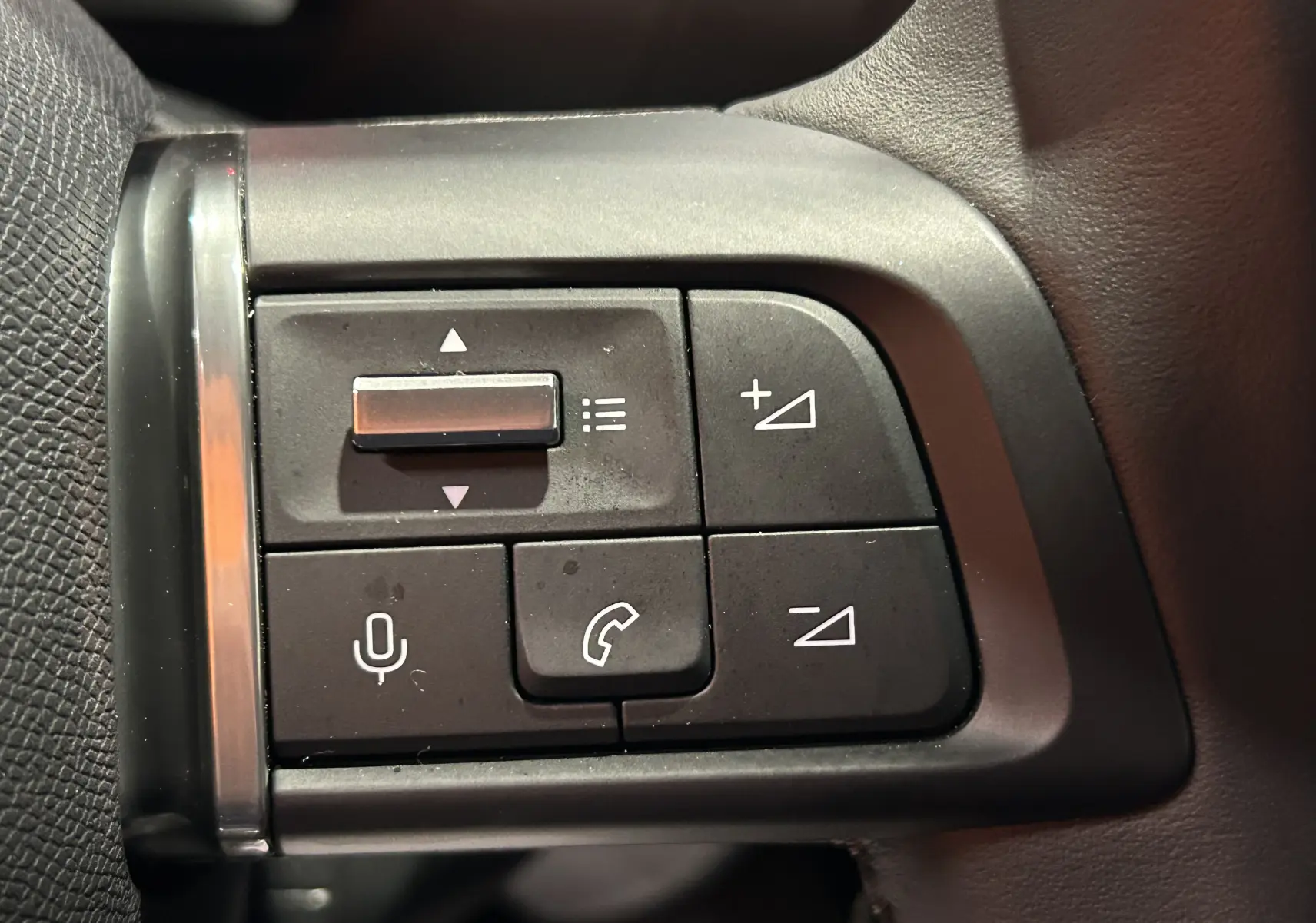 Gros plan sur les commandes noires du volant du Citroën E-C4 gris foncé, boutons de volume et téléphone visibles.