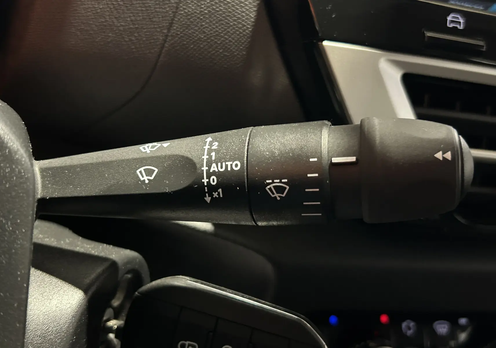 Gros plan sur la commande d’essuie-glace noir à gauche du volant dans l’habitacle du Citroën E-C4 gris foncé 2025.