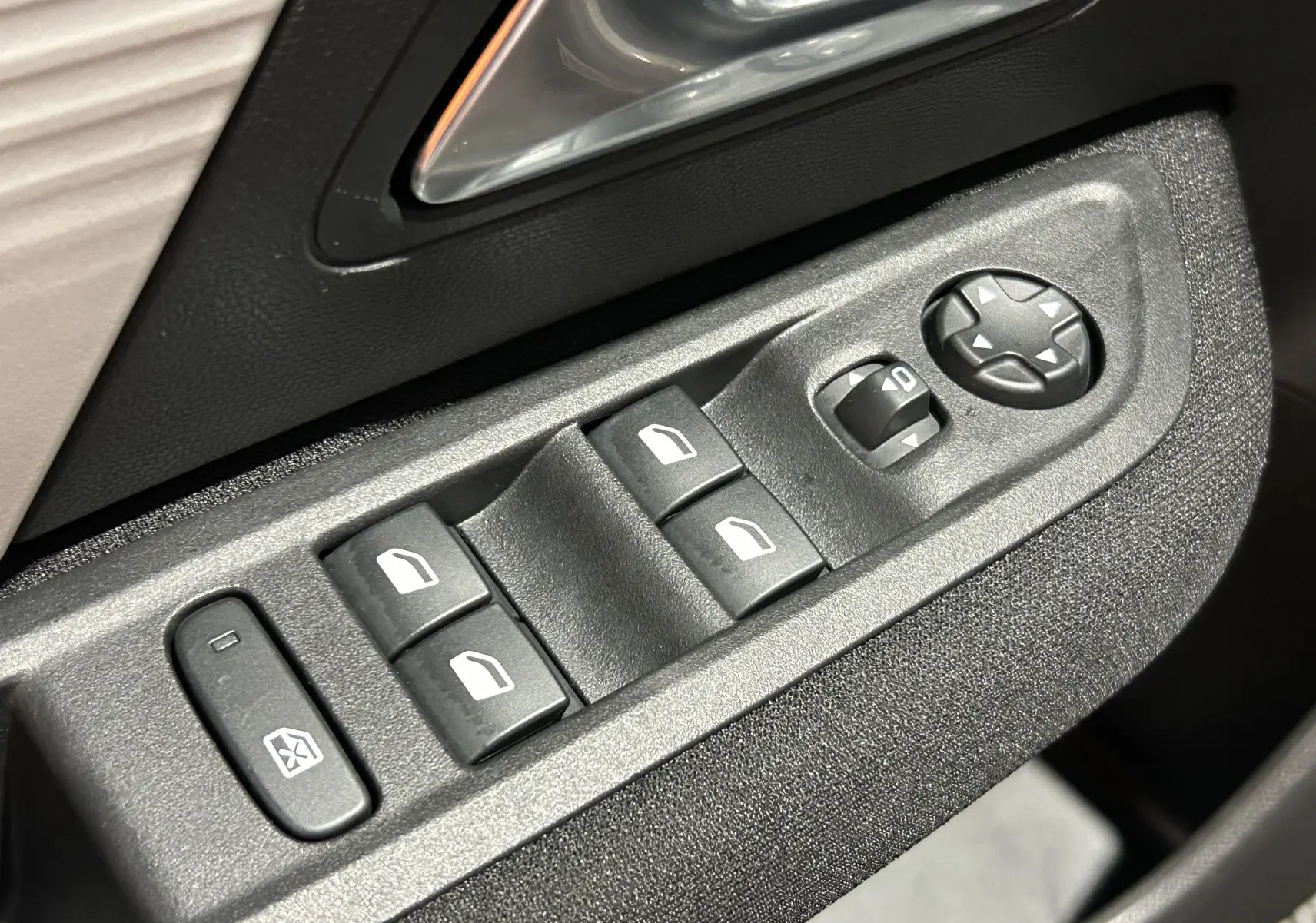 Gros plan sur les commandes de lève-vitres et réglage des rétroviseurs côté conducteur d’un Citroën E-C4 gris foncé.