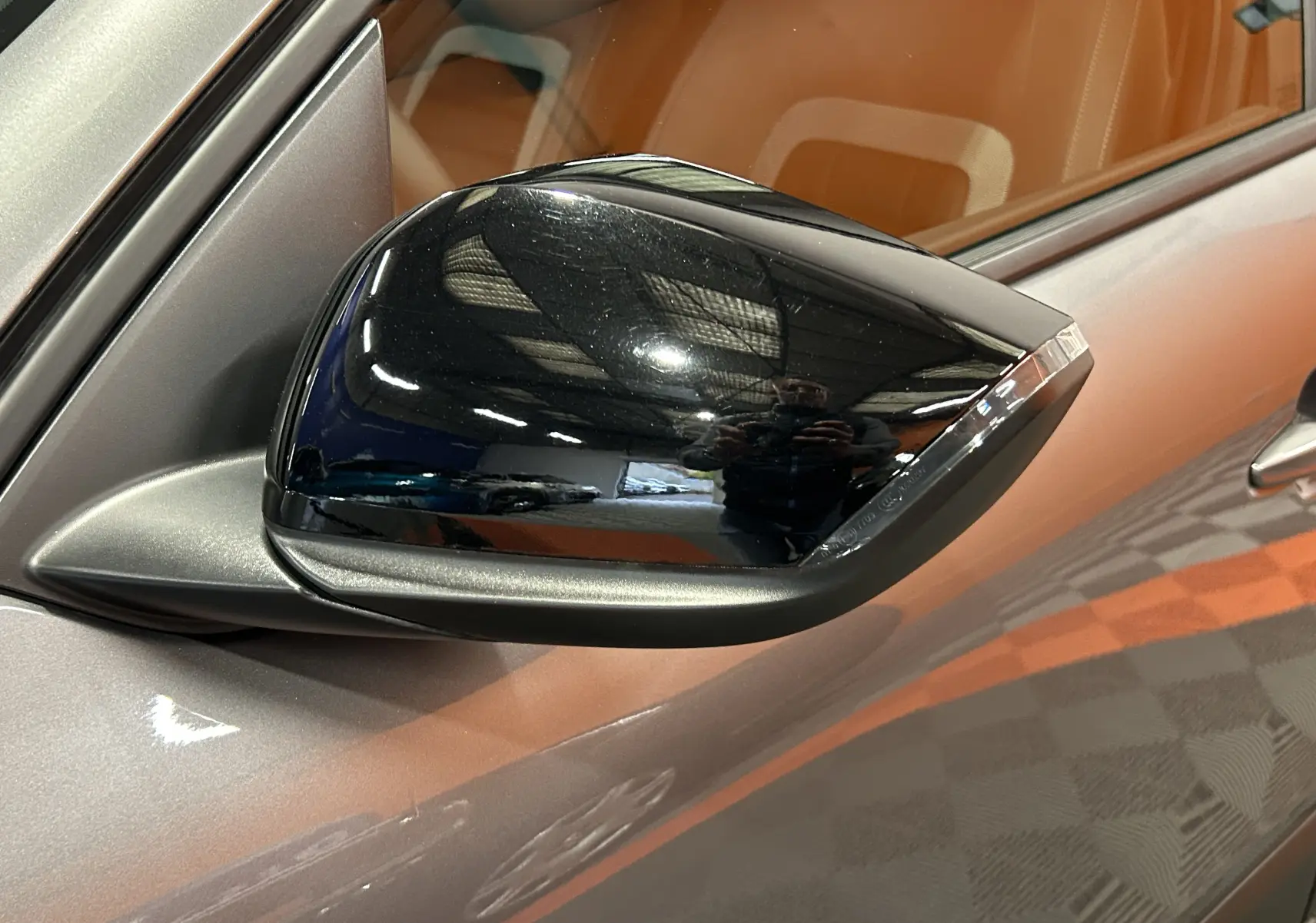 Rétroviseur noir brillant côté gauche d'une Citroën E-C4 gris foncé, avec reflet intérieur et carrosserie visible.