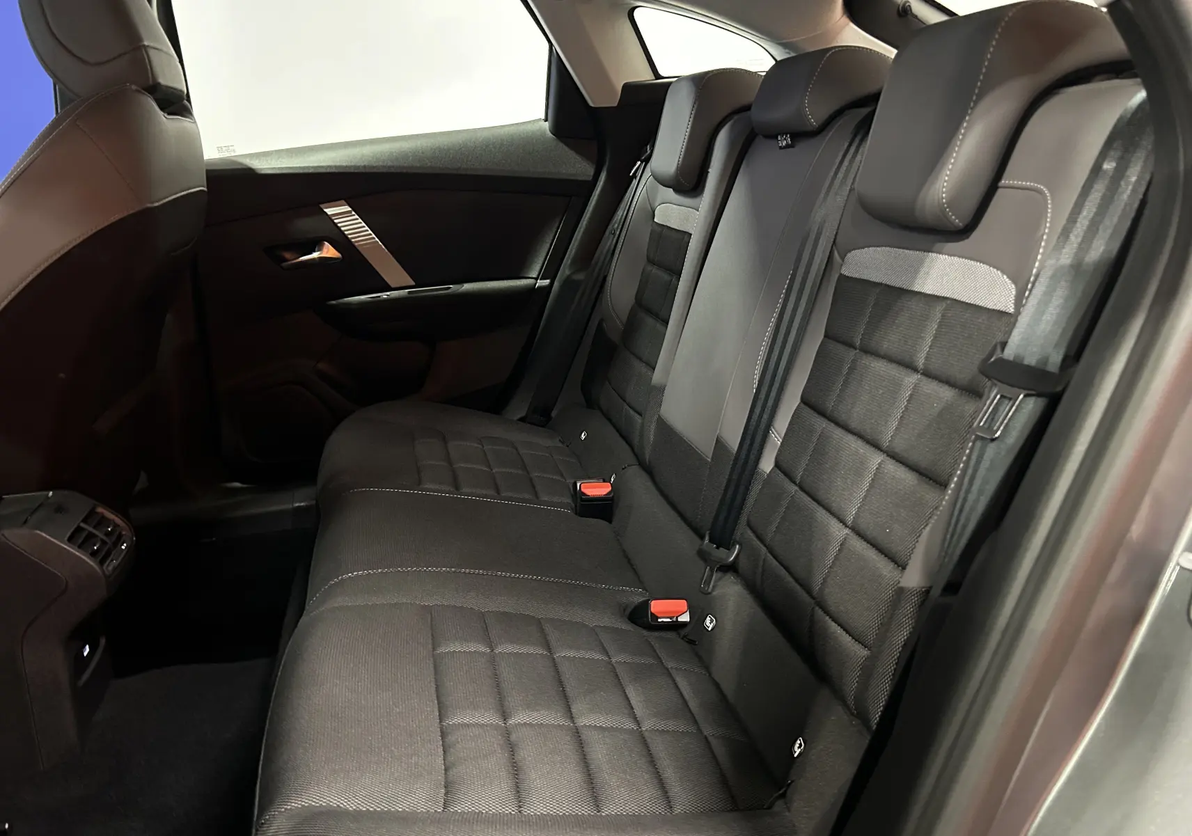 Vue intérieure côté droit des sièges arrière gris foncé du Citroën E-C4 2025 avec ceintures et appuie-têtes intégrés.