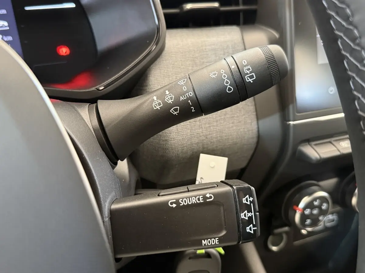 Gros plan sur les commandes de volant et essuie-glaces du tableau de bord d'une Renault Clio noire 2025.