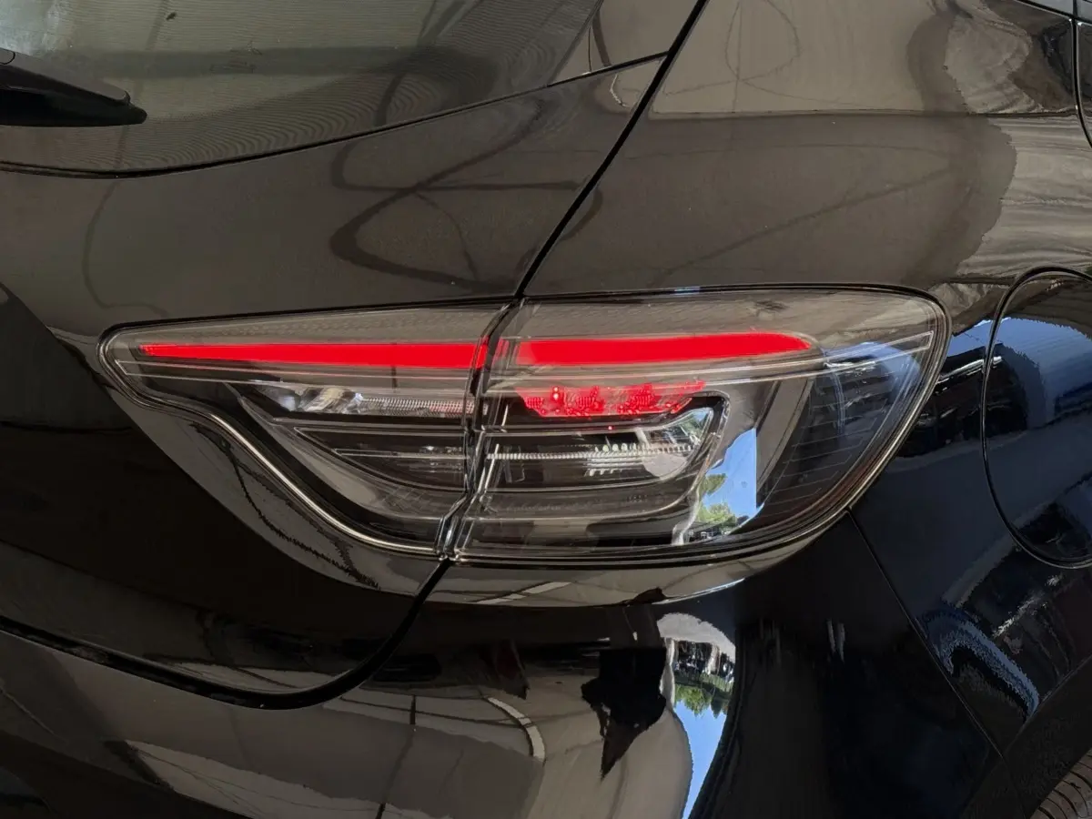 Feu arrière droit allumé sur Renault Clio noir, vue rapprochée du côté arrière du véhicule.