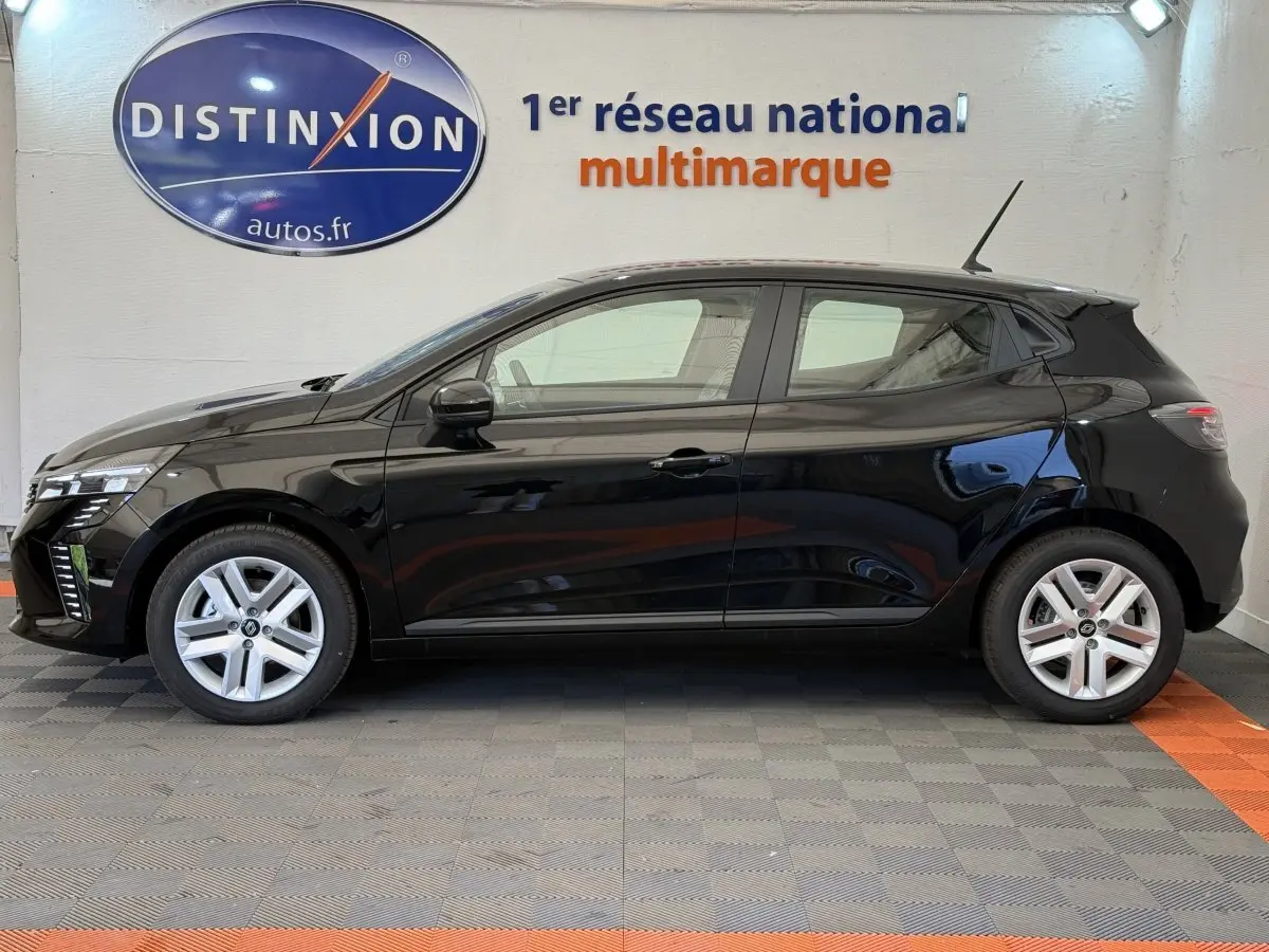 Profil côté gauche d'une Renault Clio noire 2025 garée en intérieur avec jantes argentées et antenne sur le toit.