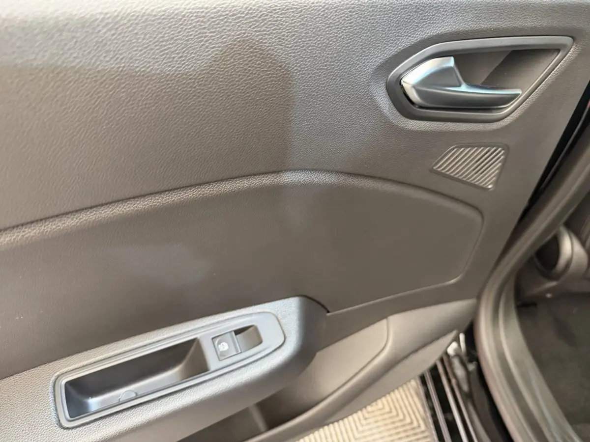 Détail de la porte avant gauche noire de la Renault Clio 2025 avec poignée argentée et commande de vitre électrique.