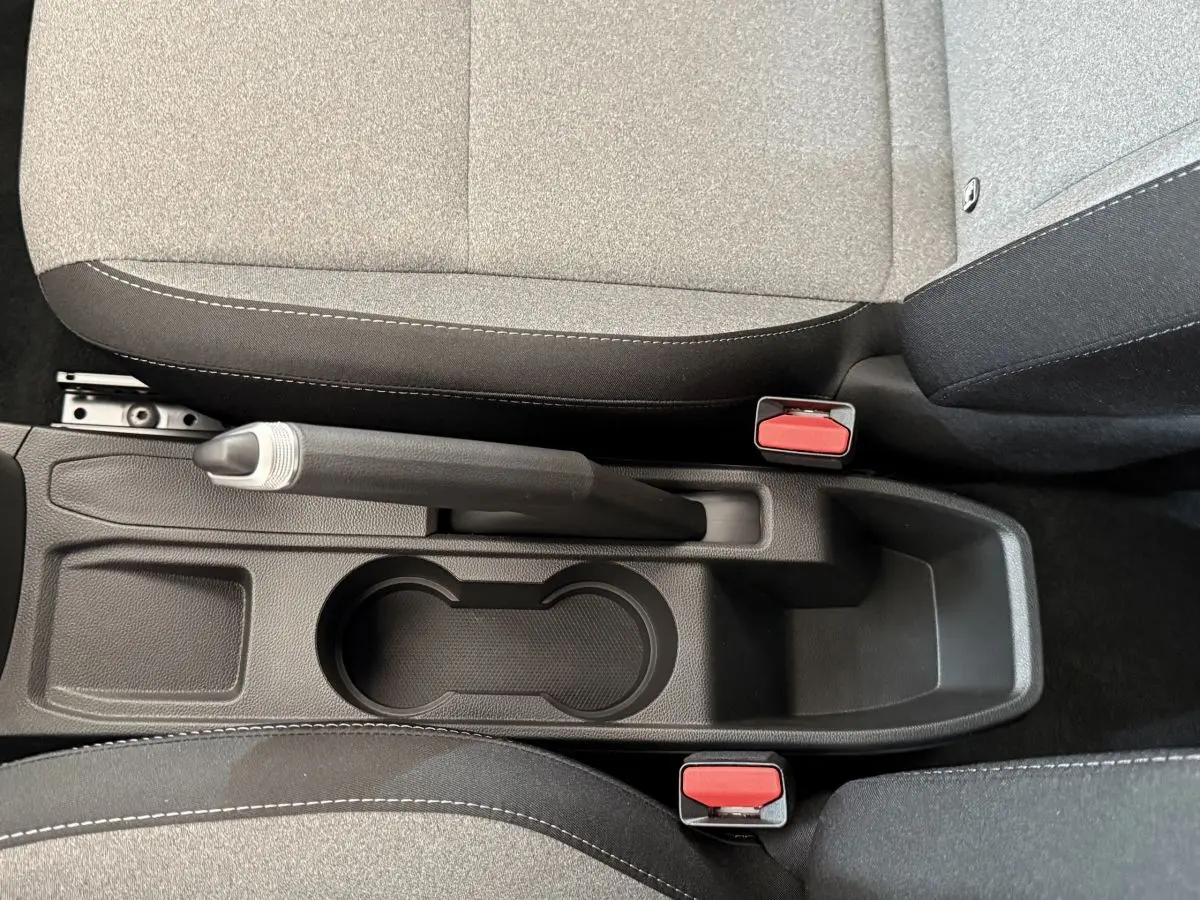 Vue rapprochée de la console centrale noire avec frein à main et sièges tissu gris de la Renault Clio 2025.