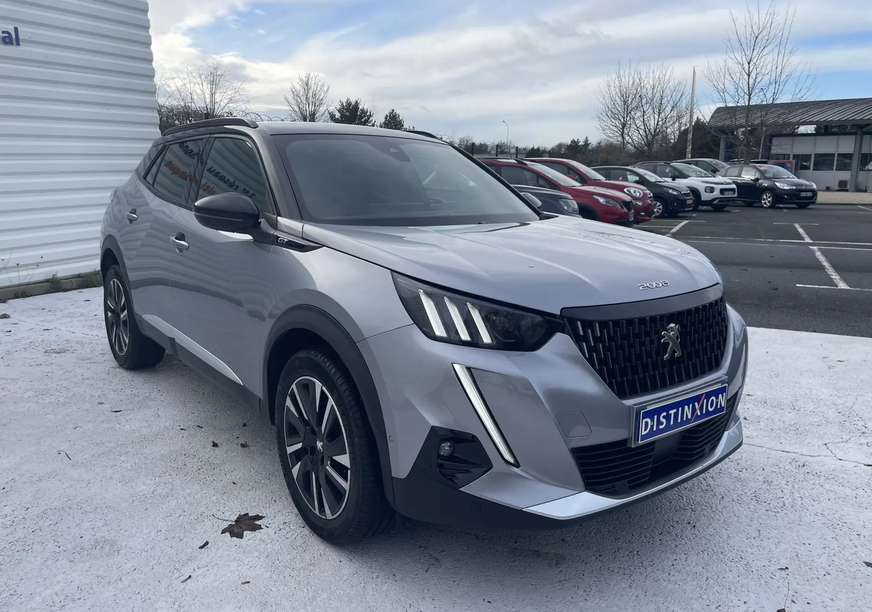 Peugeot 2008 gris Artense vue 3/4 avant droit, avec calandre noire et feux LED distinctifs en forme de griffes.