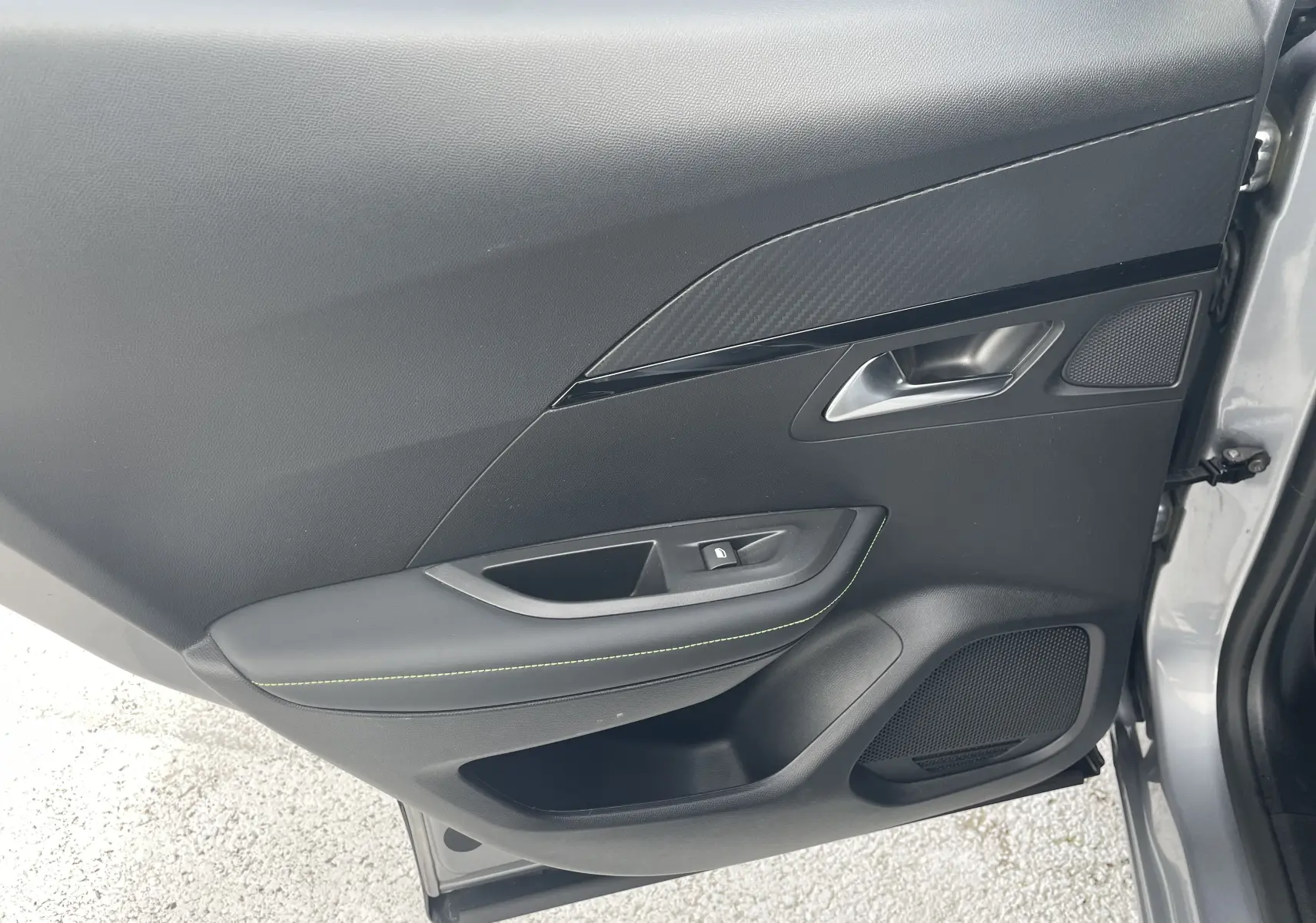 Vue rapprochée de la porte avant droite gris Artense du Peugeot 2008 2022, avec garniture noire et surpiqûres vertes.