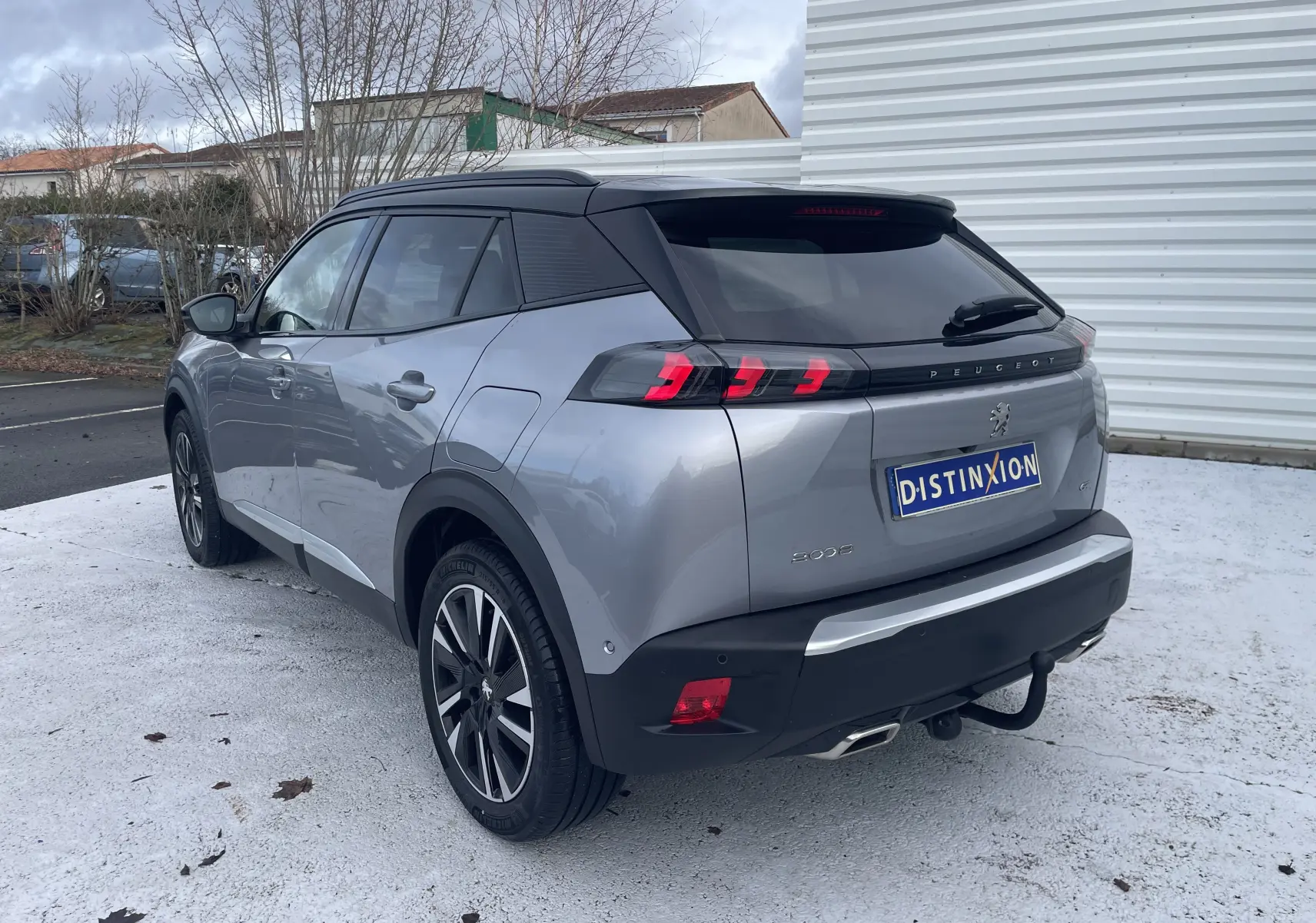 Peugeot 2008 gris Artense vue 3/4 arrière droit, toit noir, feux arrière LED et attelage visible.
