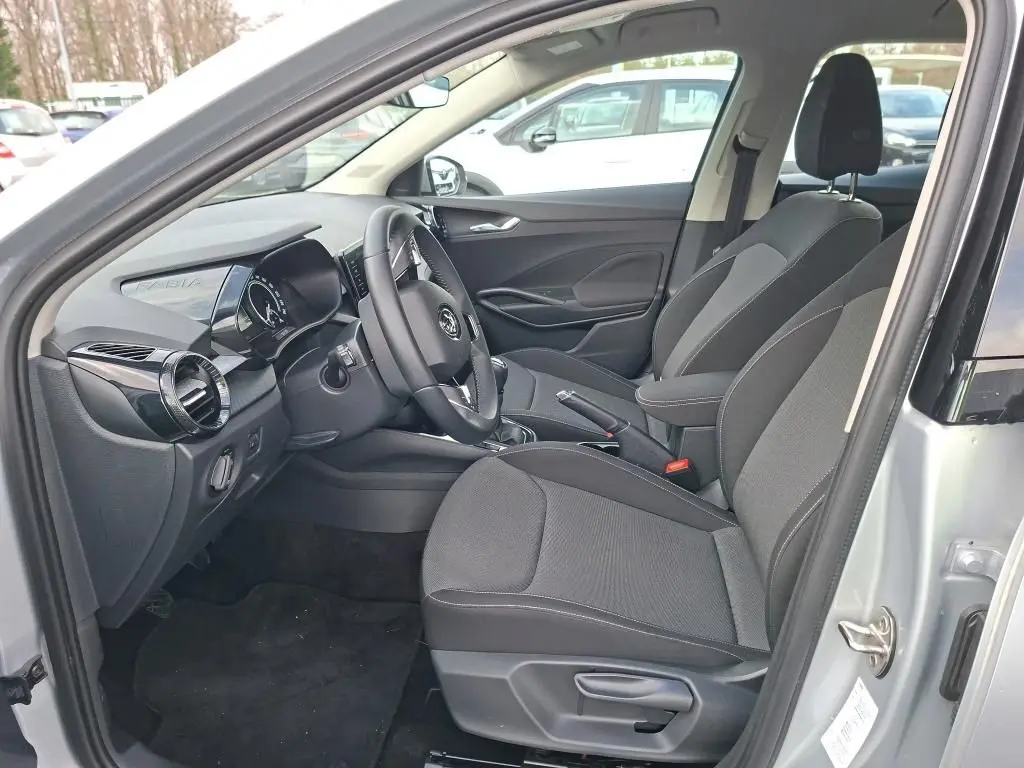 Vue intérieure côté conducteur de la Skoda Fabia Ambition 2023 gris argent, montrant sièges tissu et tableau de bord moderne.