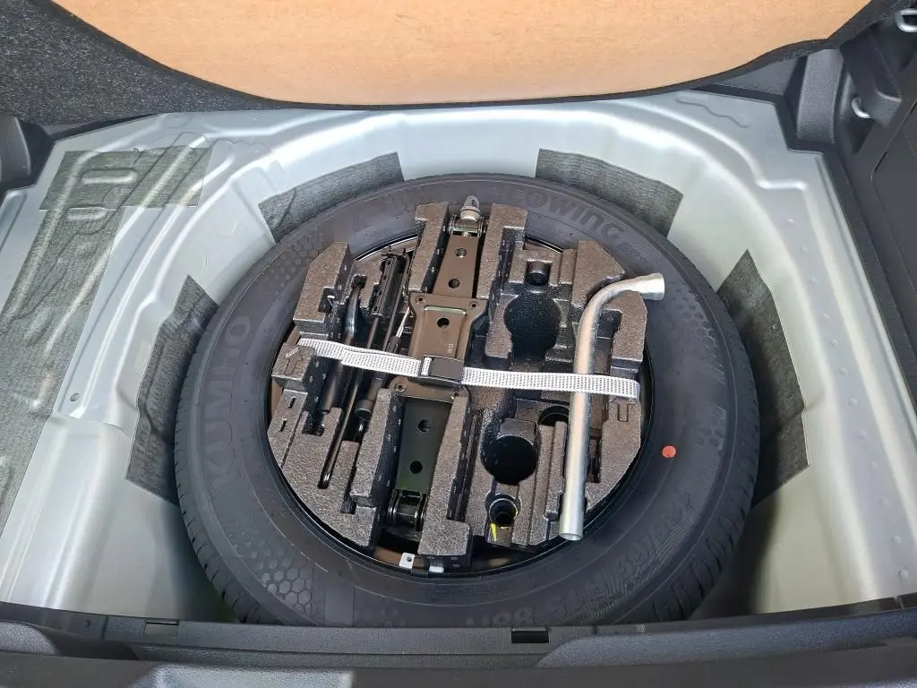 Vue plongeante sur la roue de secours et les outils de bord dans le coffre d'une Skoda Fabia gris argent 2023.