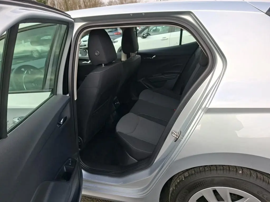 Vue côté gauche arrière de l’habitacle ouvert d’une Skoda Fabia Ambition gris argent 2023, sièges noirs visibles.