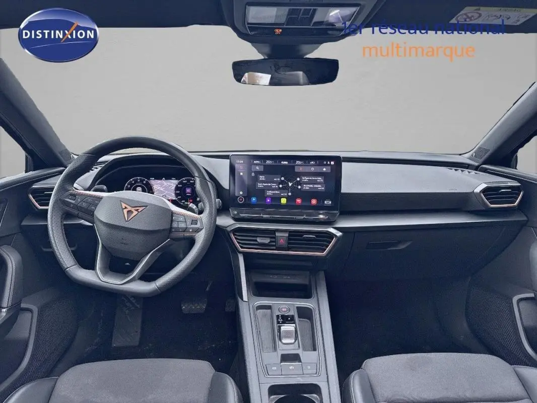 Vue intérieure avant du CUPRA Leon ST 2024, tableau de bord noir avec écran tactile et volant cuir multifonction.
