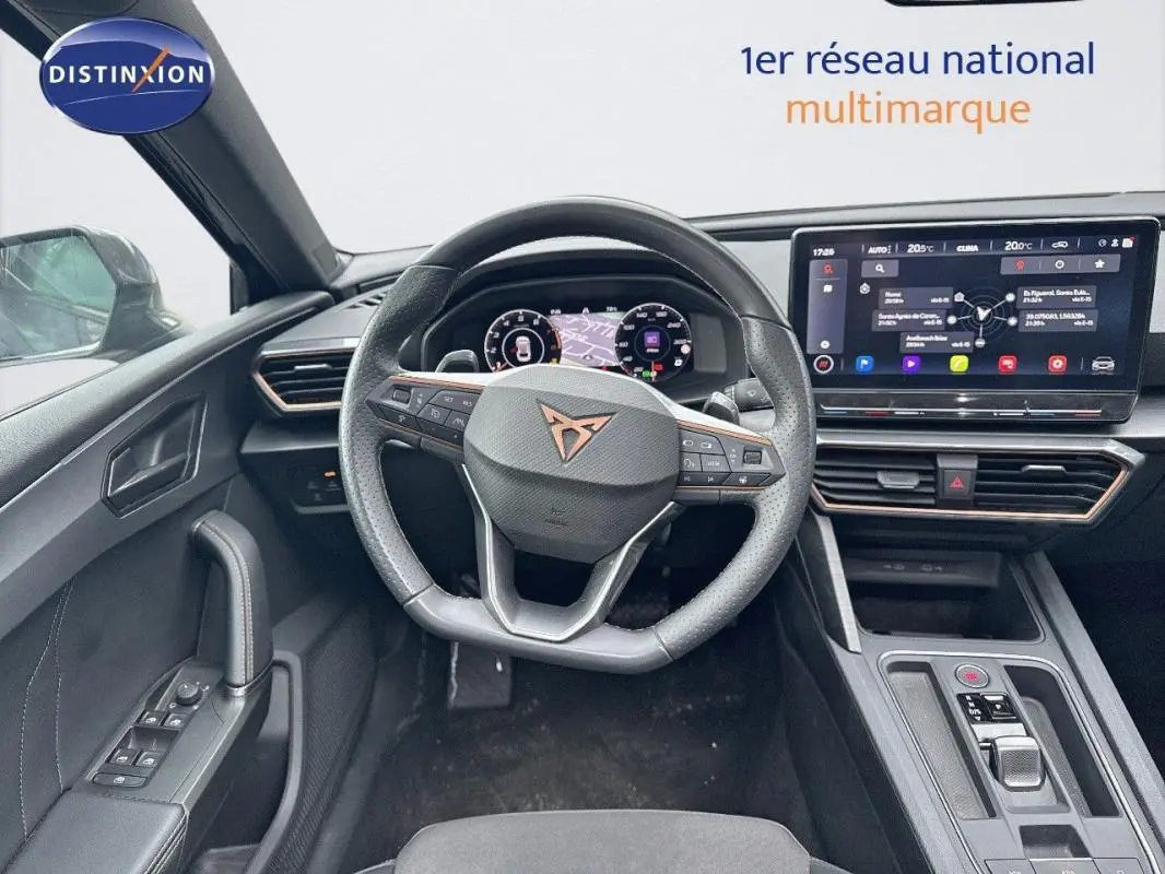 Vue intérieure centrée sur le volant cuir et l'écran tactile du tableau de bord d'une CUPRA Leon ST 2024.