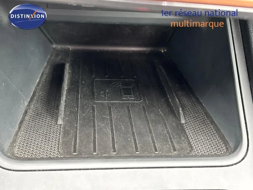 Gros plan sur le chargeur sans fil noir intégré dans la console centrale de la CUPRA Leon ST 2024 gris.