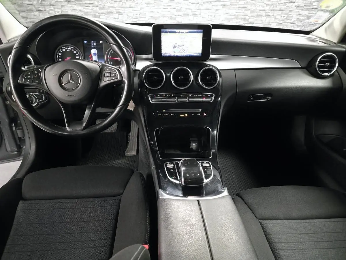 Vue intérieure avant de la Mercedes Classe C 200 d 2018, tableau de bord noir avec écran central et volant multifonctions.
