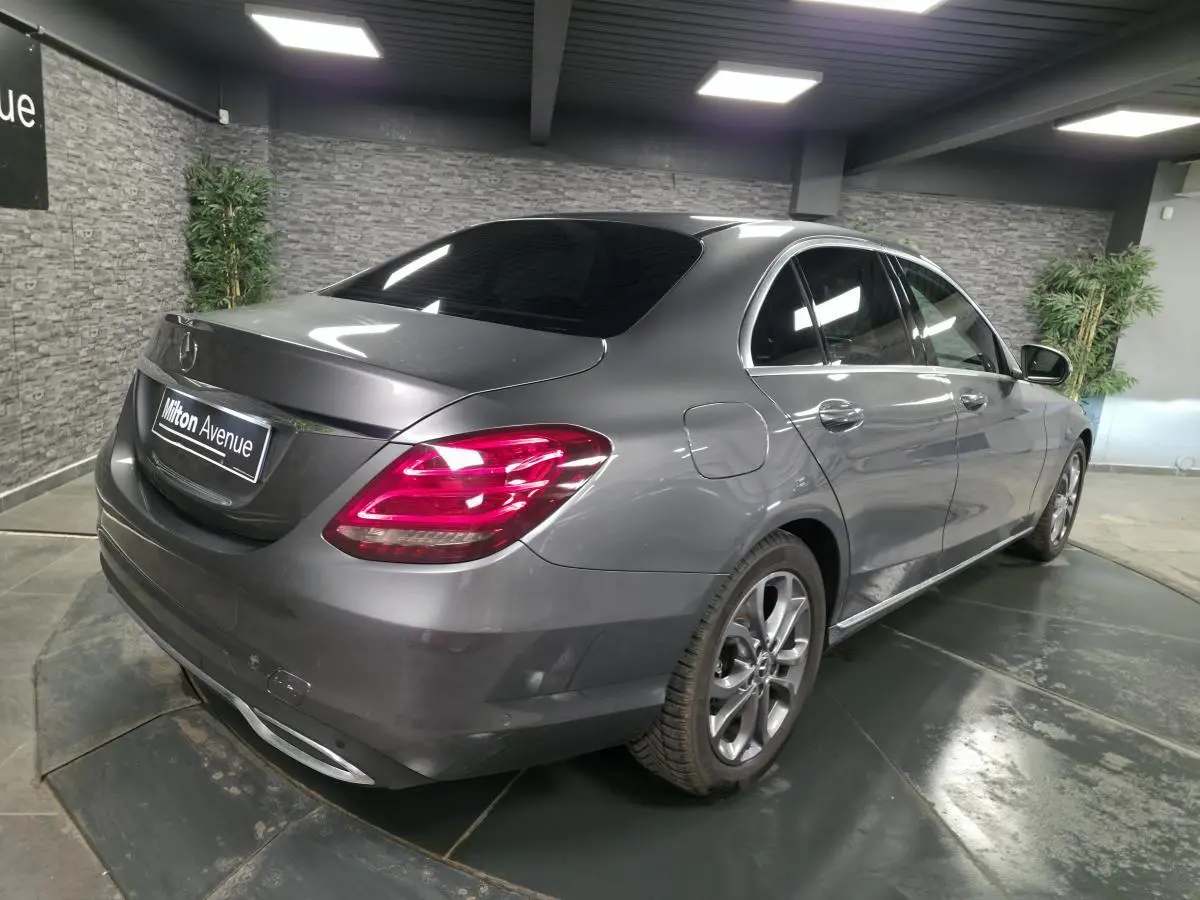 Mercedes Classe C 200 d gris métallisé vue 3/4 arrière droit, avec jantes alliage 17 pouces et feux arrière LED allumés.