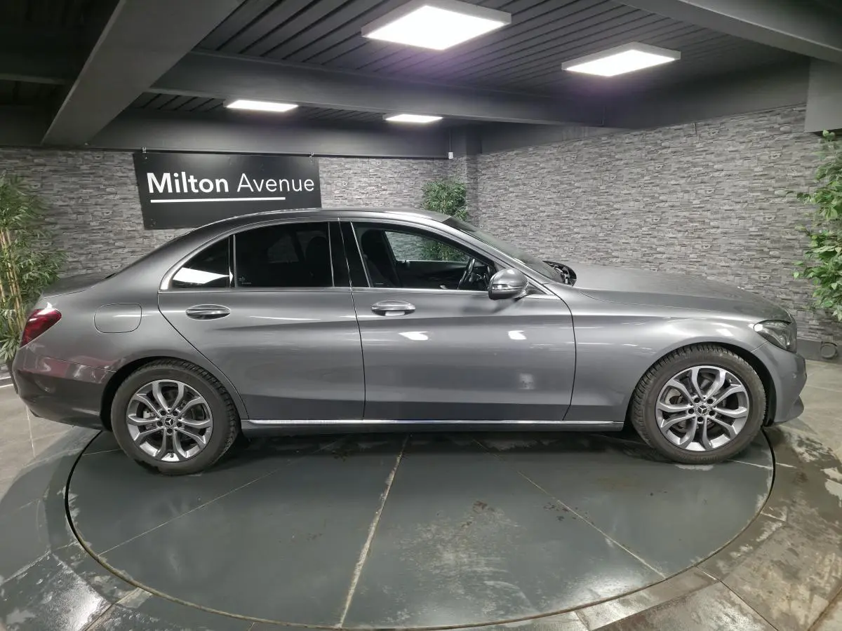 Profil côté droit d'une Mercedes Classe C gris métallisé avec jantes alliage 17 pouces dans un showroom.