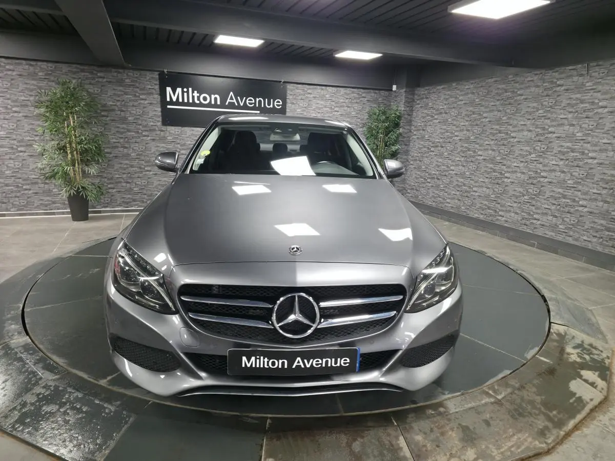 Vue avant d'une Mercedes Classe C gris métallisé avec calandre à deux lamelles et logo étoile central, en showroom.