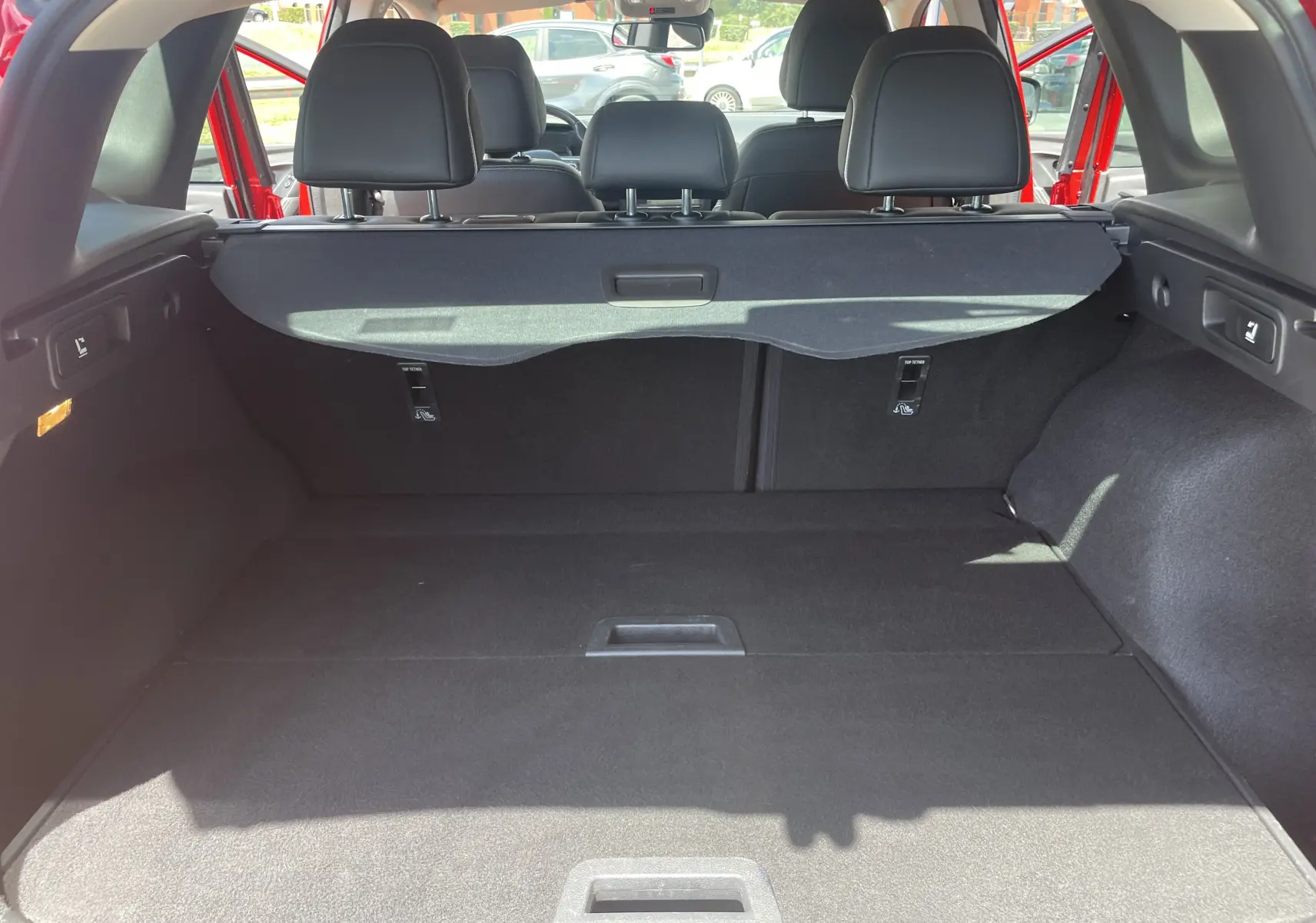 Vue arrière du coffre spacieux du Renault Kadjar rouge flamme 2018, avec cache-bagages et sièges arrière rabattables.