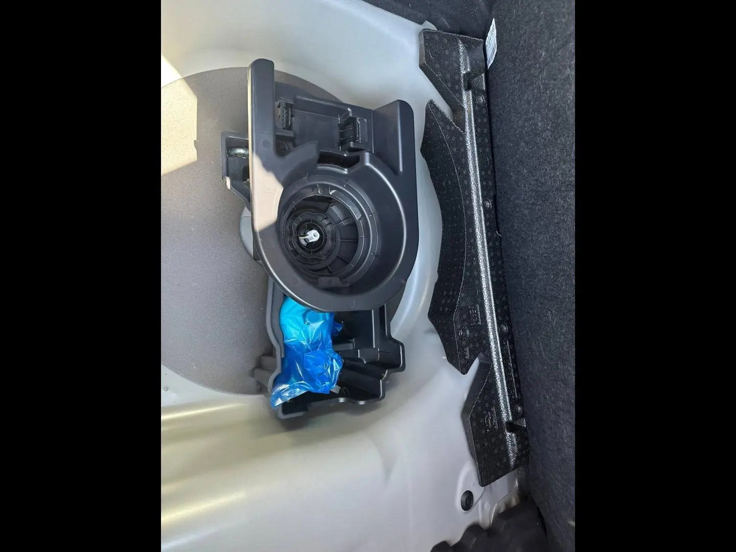 Vue rapprochée du coffre de la Peugeot 208 2025 gris Selenium, montrant le rangement et l’emplacement de la roue de secours.