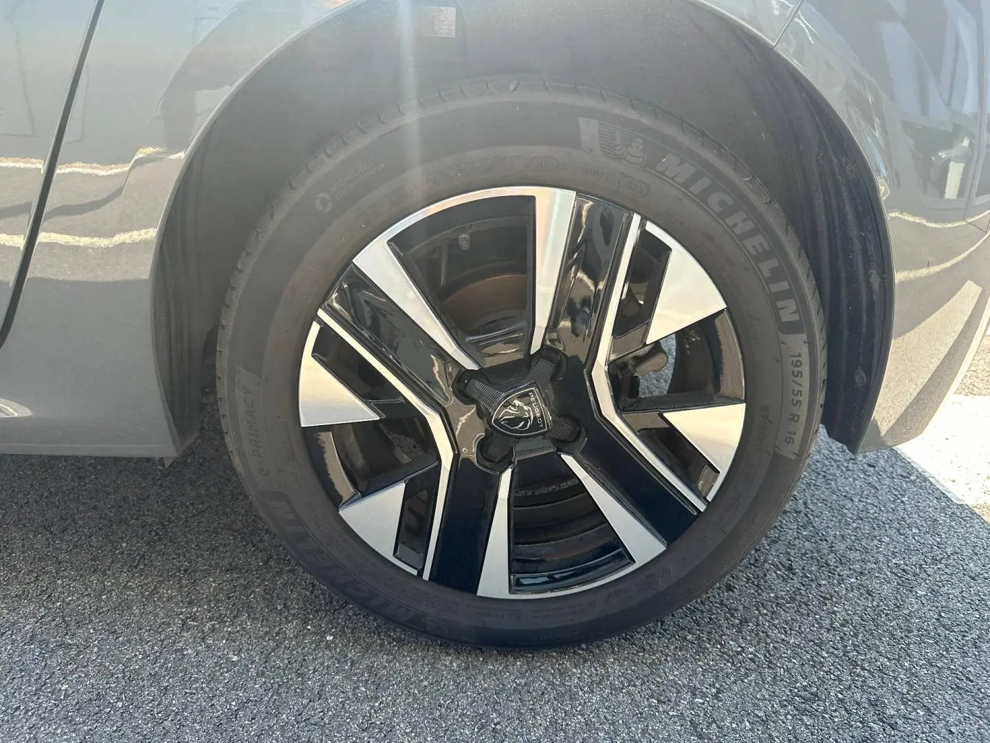Gros plan sur la jante alu noire et argentée de la roue avant droite d’une Peugeot 208 gris Selenium.