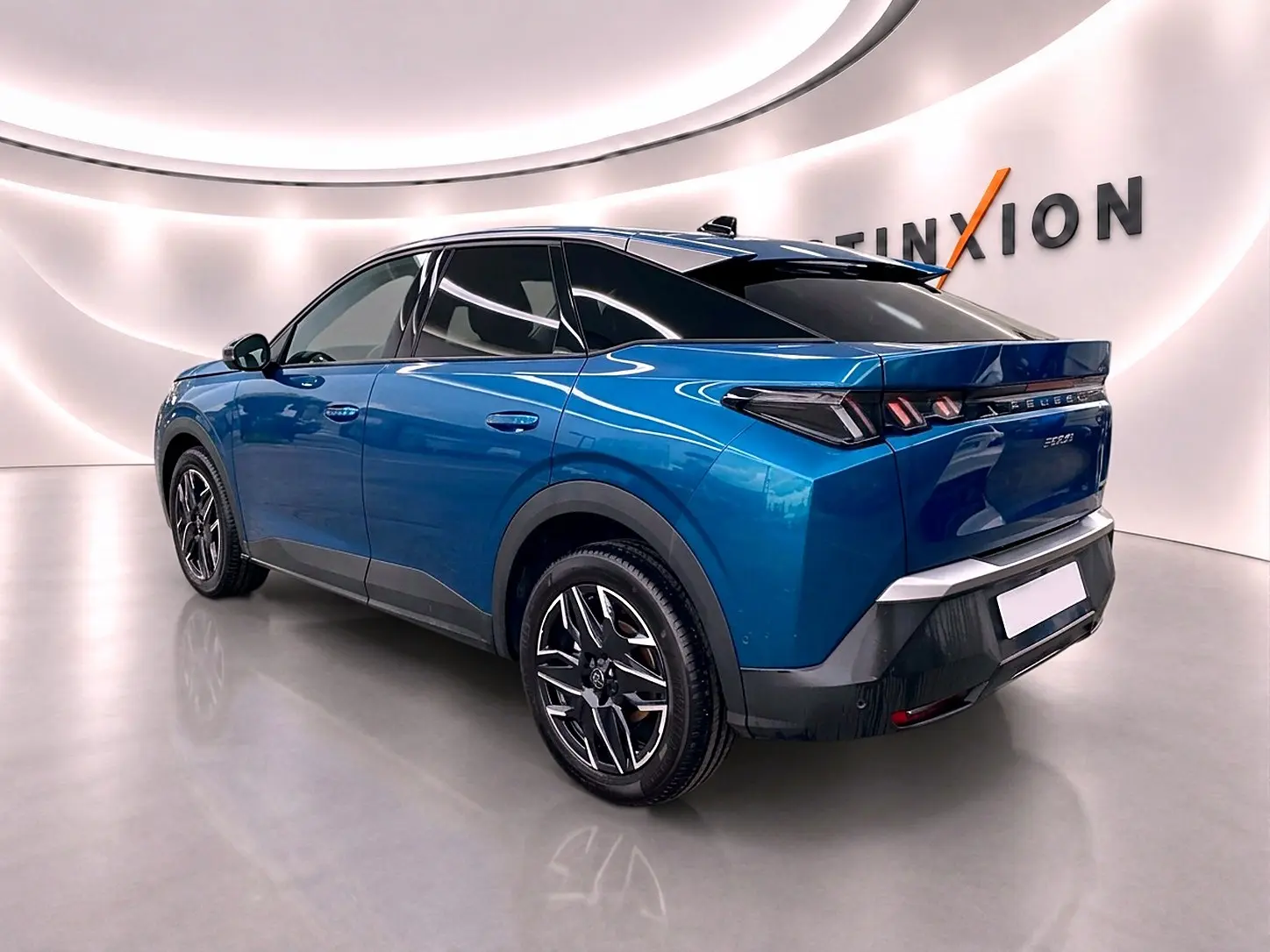 Vue 3/4 arrière droite du Peugeot 3008 bleu 2025 avec jantes alliage et toit noir brillant dans un showroom lumineux.